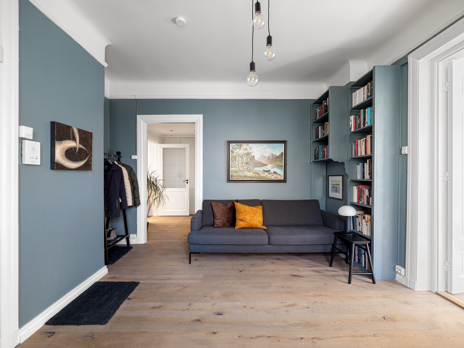 Hallen er romslig og er i dag innredet som en ekstra stue med plassbygde bokhyller Galleribilde