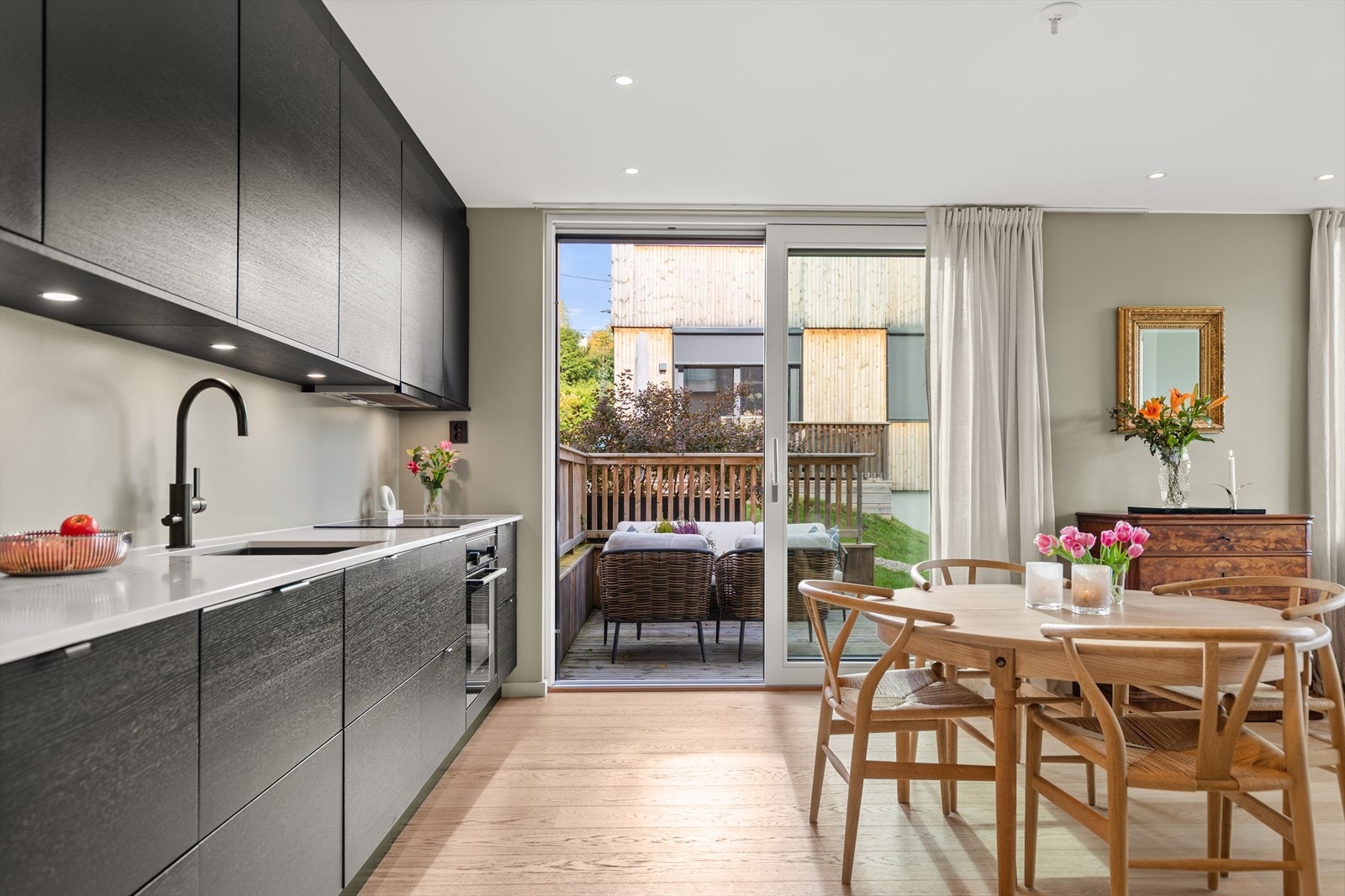 Hvitevarer bestående av induksjon koketopp, stekeovn, kjøl/frys og oppvaskmaskin. Ventilator over kokesone. Galleribilde