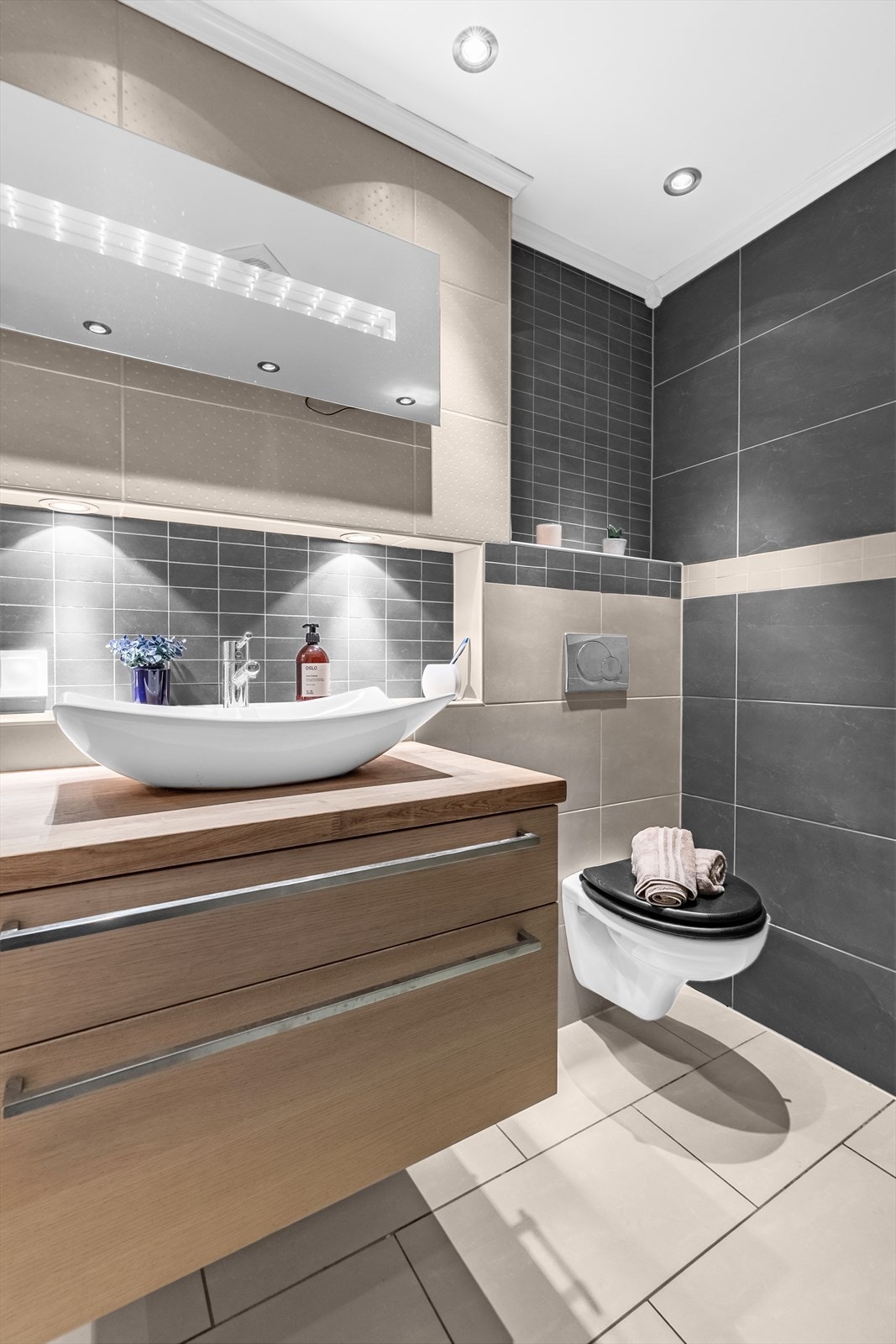 Rommet er utstyrt med innfellbare dusjdører, mekanisk periodisk avtrekk, opplegg for vaskemaskin, rørfordelingsskap, varmtvannsbereder, veggmontert wc og servantskap med ett-greps blandebatteri. Galleribilde