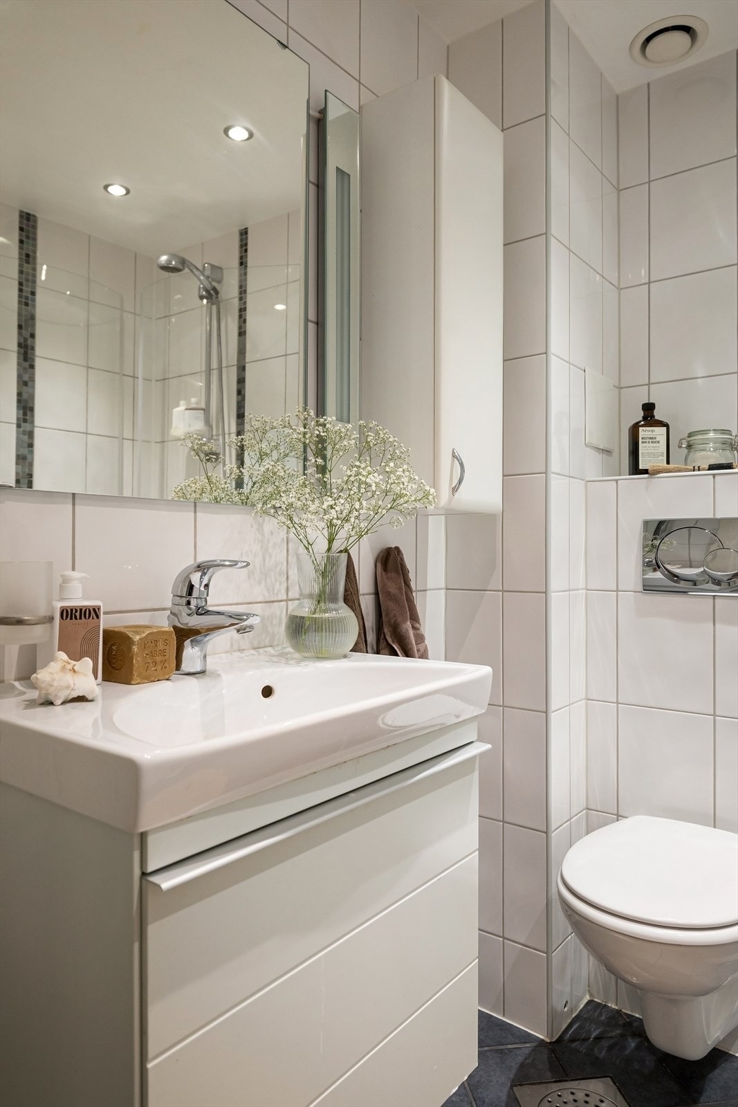 Baderommet er innredet med heldekkende servant med skuffeinnredning i hvit utførelse, samt speil med belysning over Galleribilde