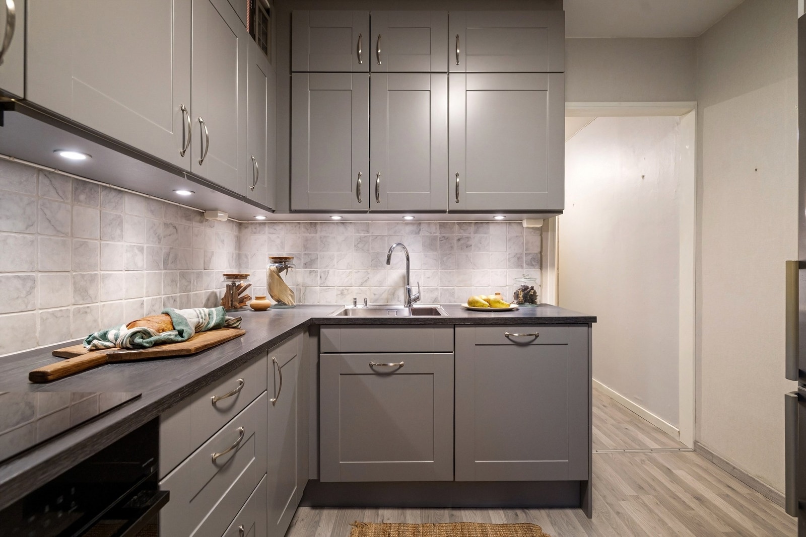 Pene fliser er belagt mellom benkeplate og overskap, samt både overskapsbelysning og stikkontakter Galleribilde