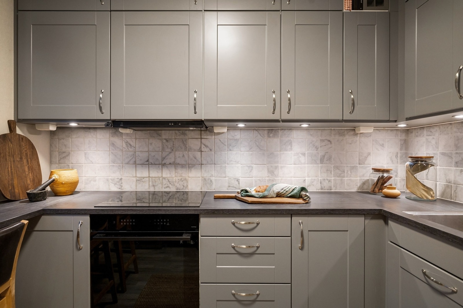 Integrerte hvitevarer som oppvaskmaskin, stekeovn og induksjonstopp, samt integrert ventilator med kullfilter over. Frittstående vinkjøler og kjøleskap med frysedel Galleribilde