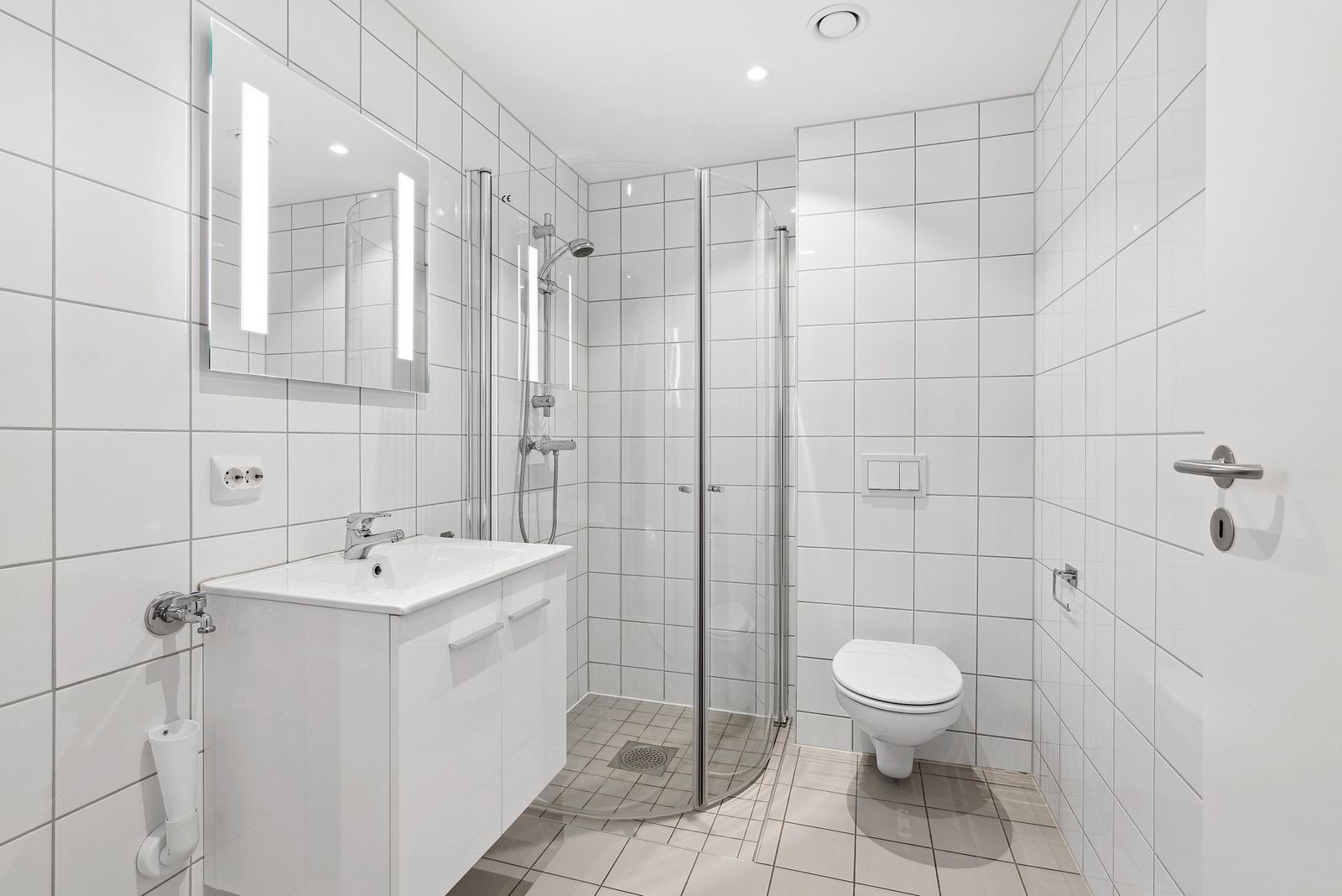 Pent, flistlagt bad med varmekabler i gulv og opplegg for vaskemaskin Galleribilde