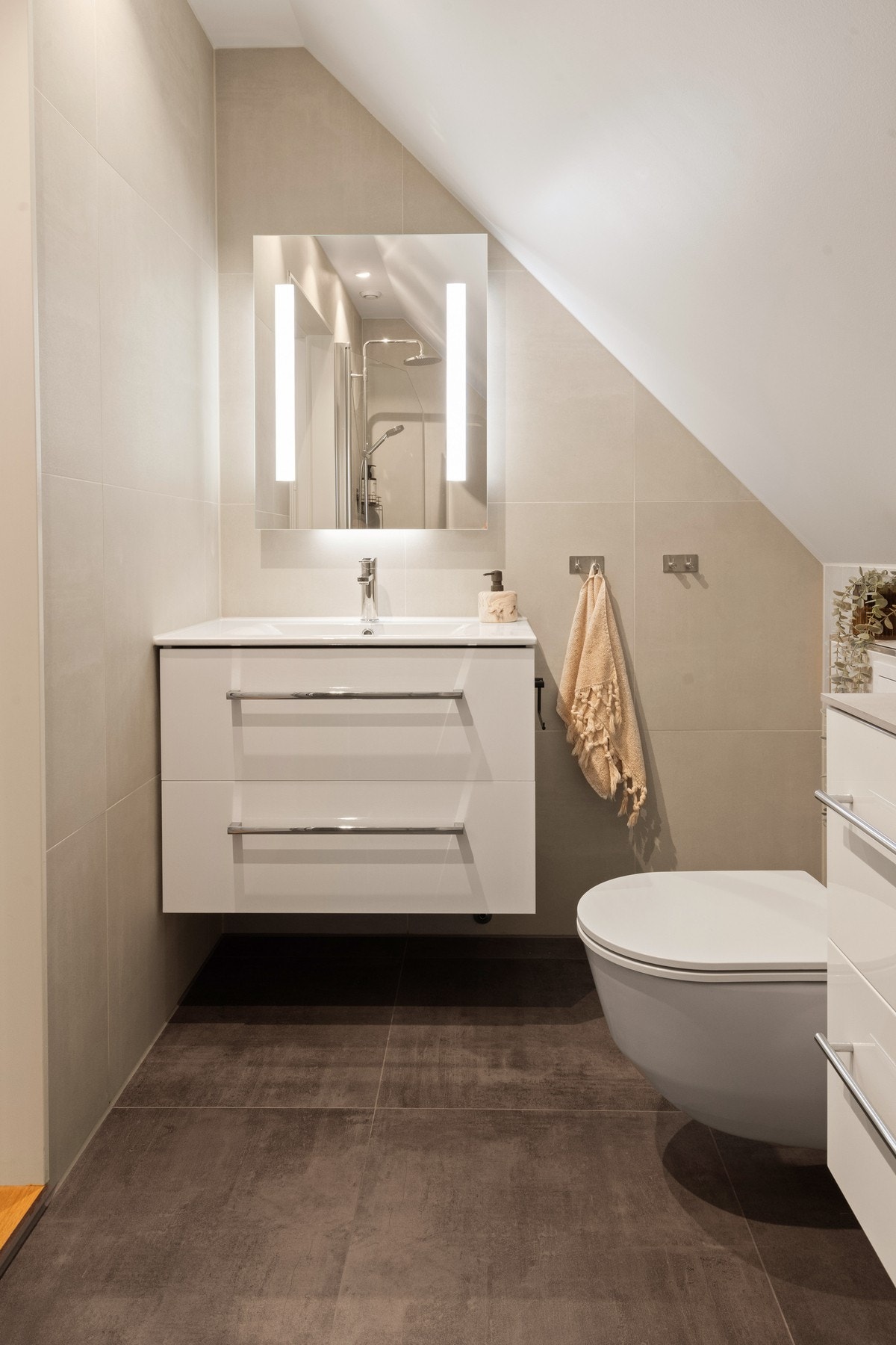 Badet i andre etasje er pent og funksjonelt med vegghengt toalett, dusjhjørne og servant med speil Galleribilde