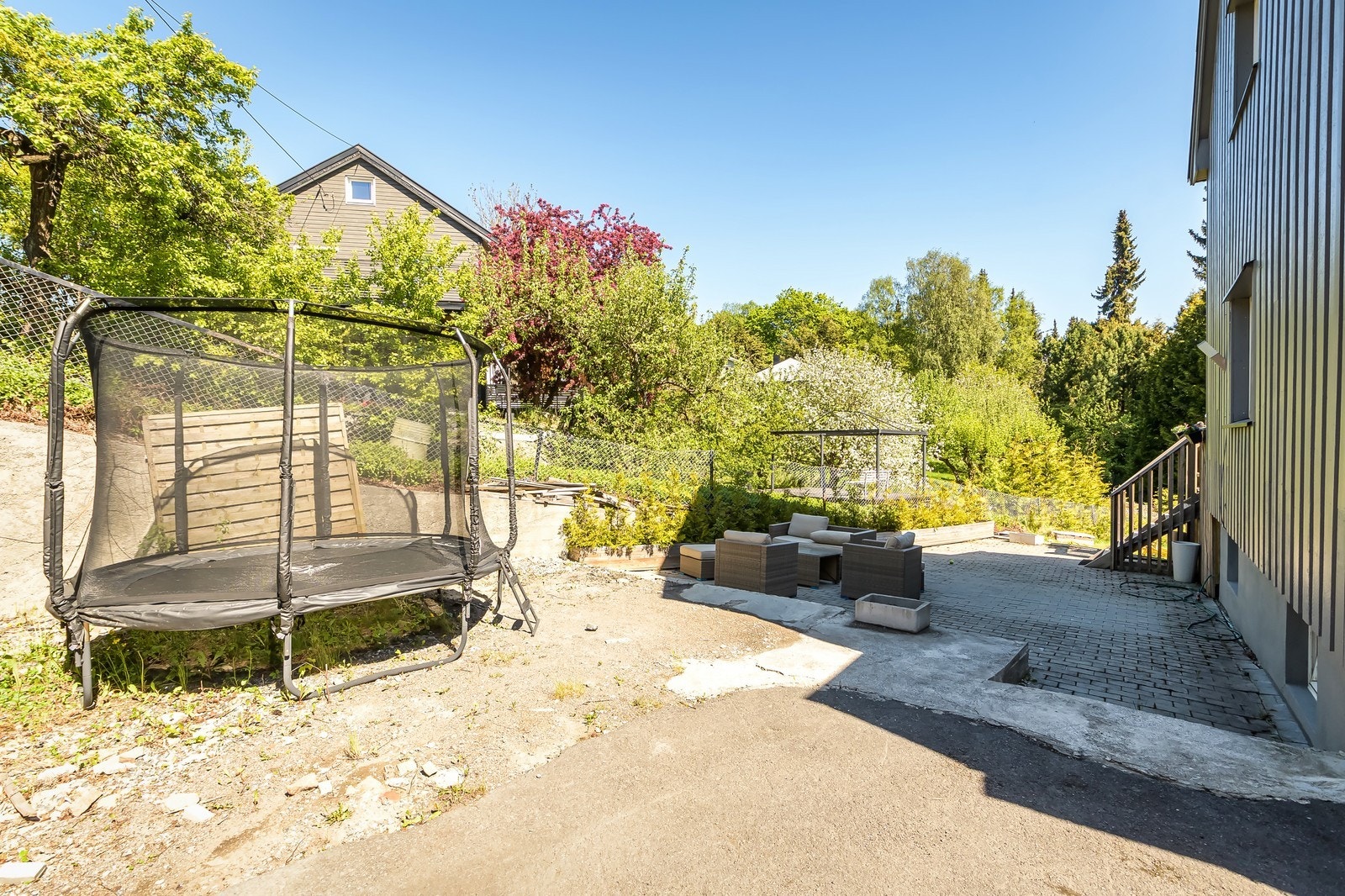Uteplass med trampoline og steinlagt område. Galleribilde