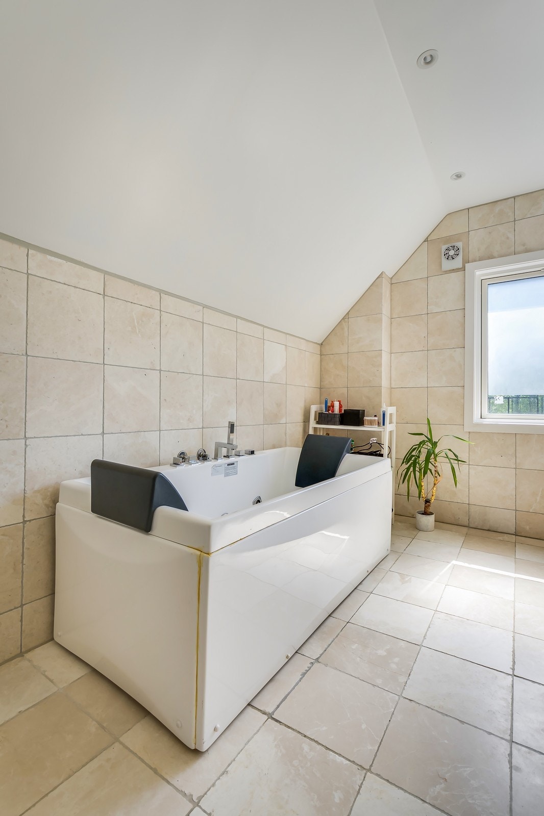 Stort badekar med nakkestøtter og beige fliser. Galleribilde