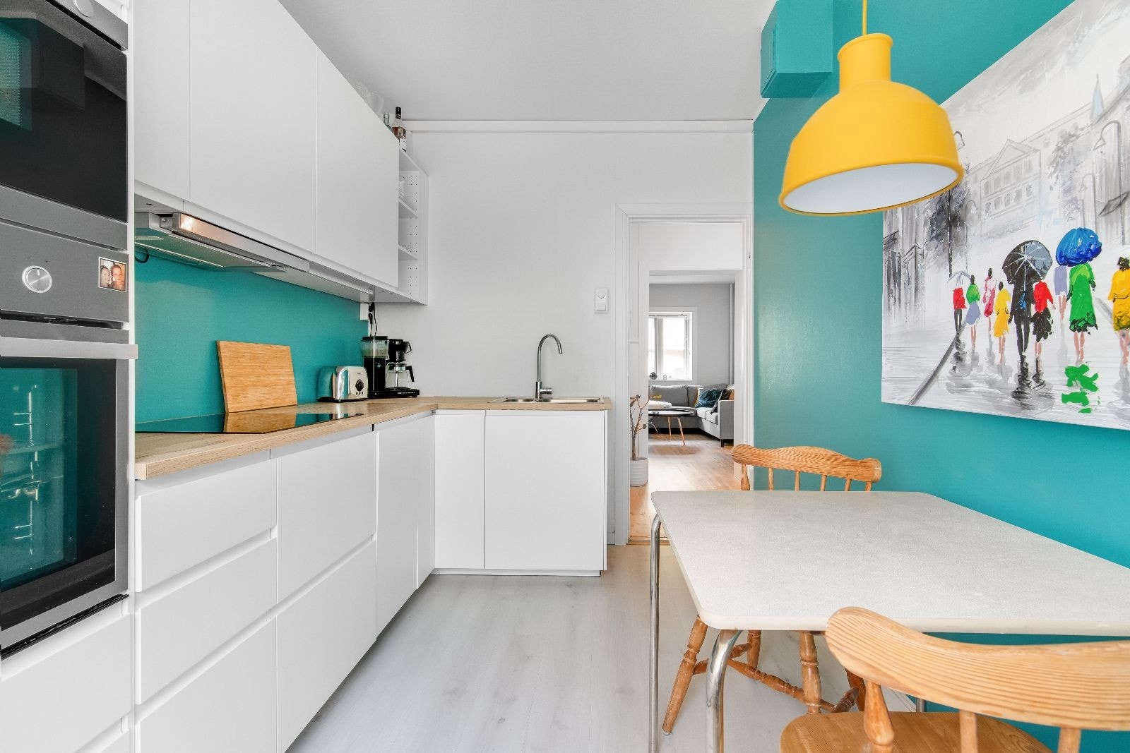 Pent kjøkken med integrerte hvitevarer og plass til spisebord. Veggene er malt i etterkant av bilder Galleribilde