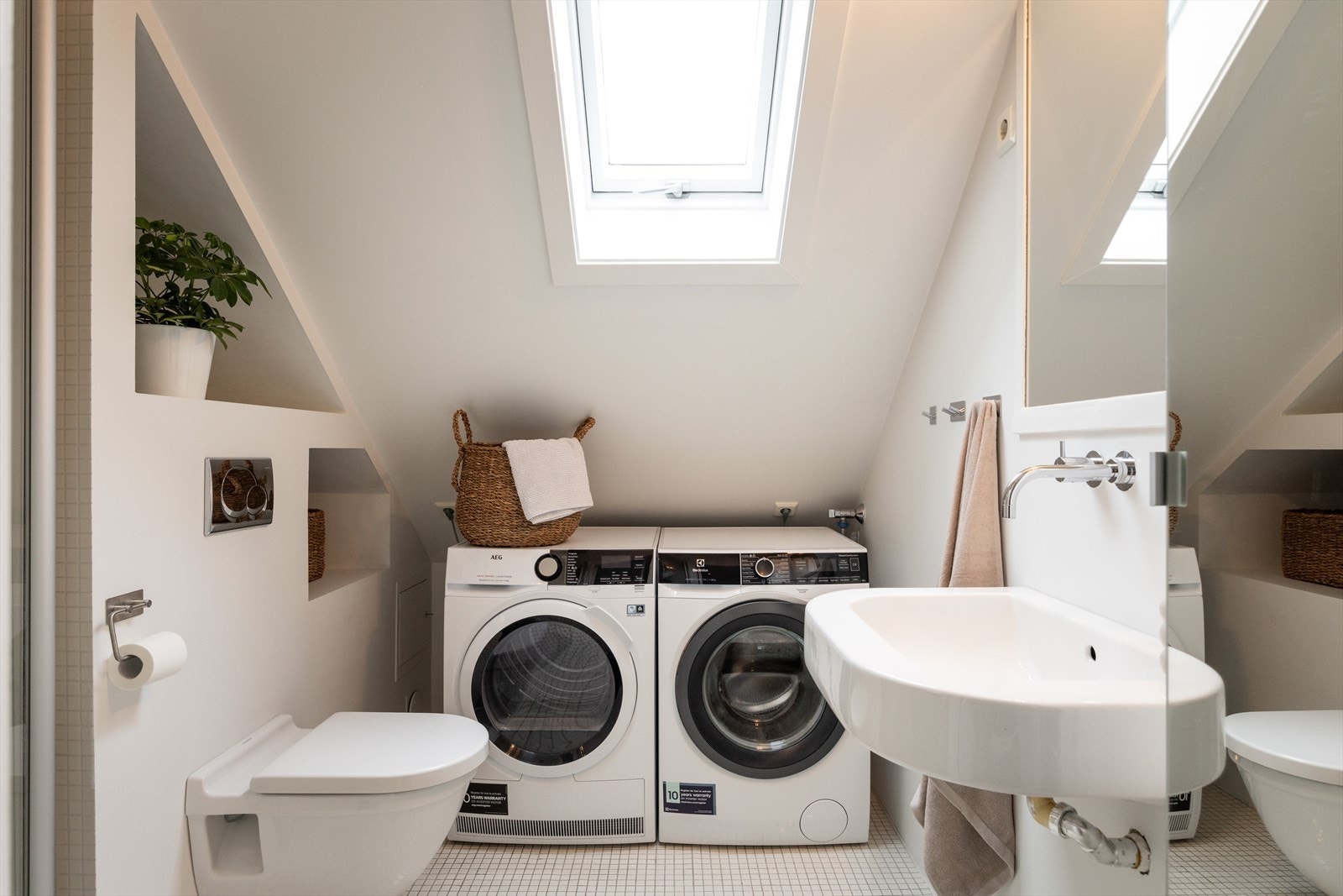 Badet har stilige mosaikkfliser med gulvvarme. Her er det også opplegg og god plass til både vaskemaskin og tørketrommel. Galleribilde