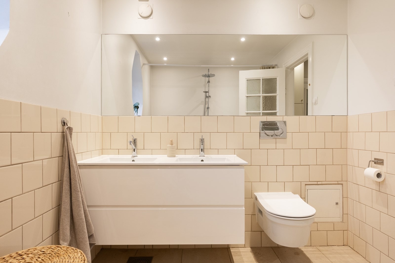 Badet er innredet med vegghengt toalett, dobbel servant med tilhørende skuffer, innfelt speil og badekar med dusj. Galleribilde