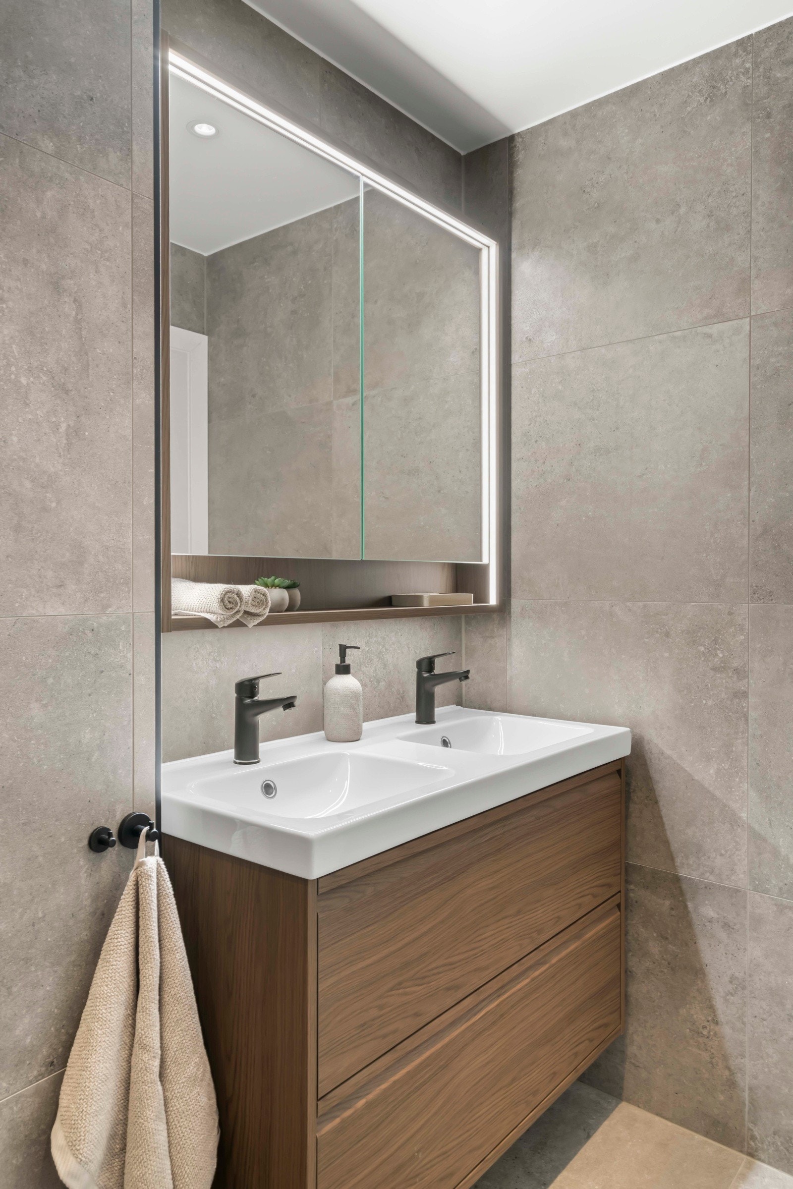 Her får du store fliser, nedsenket dusjnisje med glassvegg, dobbel servant, speilskap med belysning, vegghengt toalett og håndkletørker Galleribilde