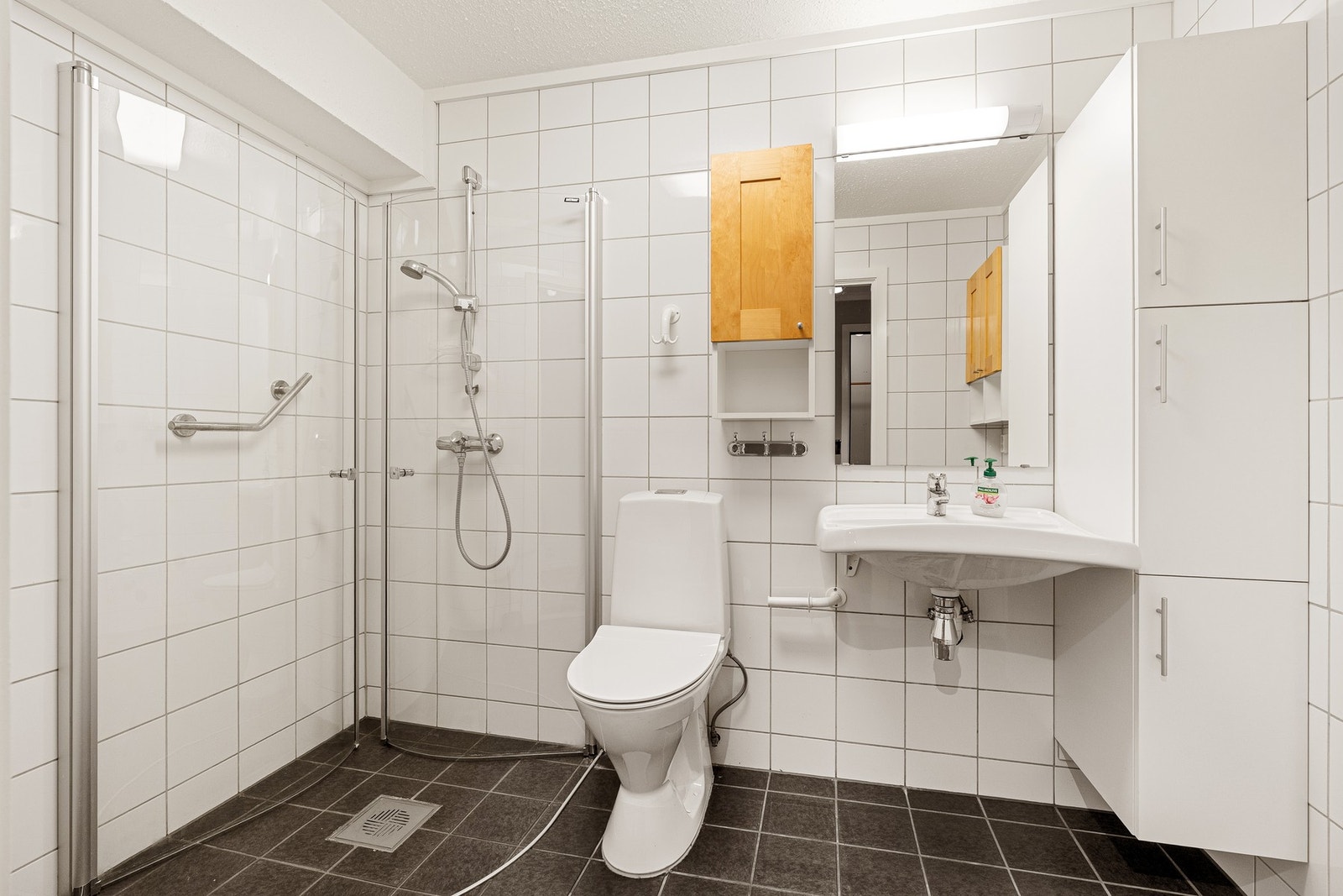 Badet er helfliset og er innredet med dusjhjørne, servant og toalett. Her er det også opplegg til vaskemaskin. Galleribilde