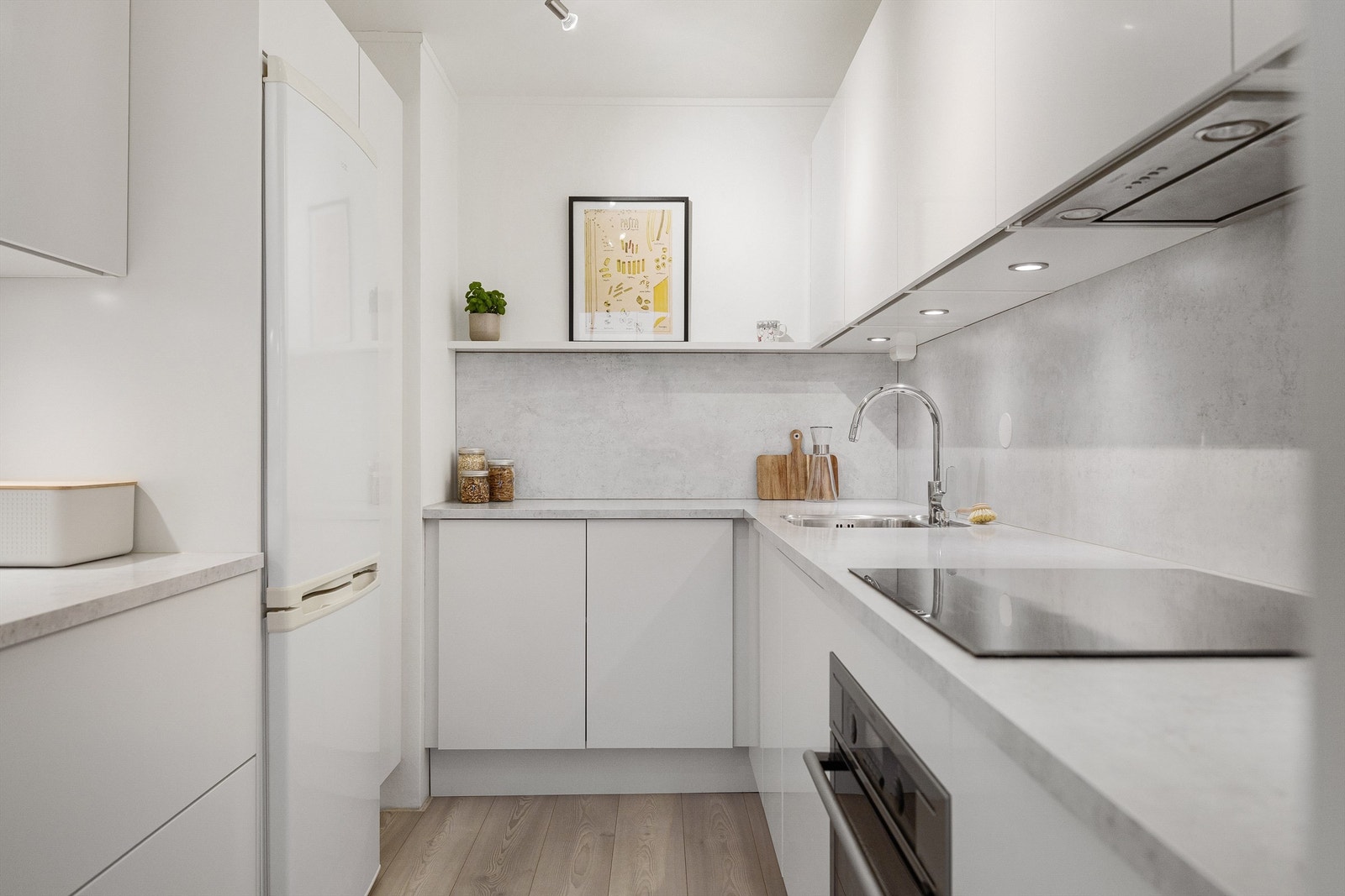 Integrert komfyr, oppvaskmaskin og induksjonstopp med kjøkkenvifte med kullfilter over. Kjøleskap med fryser i nisje Galleribilde