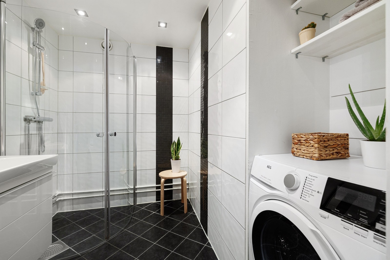 Badet er innredet med hel servantplate med servantskap, speil på vegg over og dusjhjørne med innfellbare glassdører Galleribilde