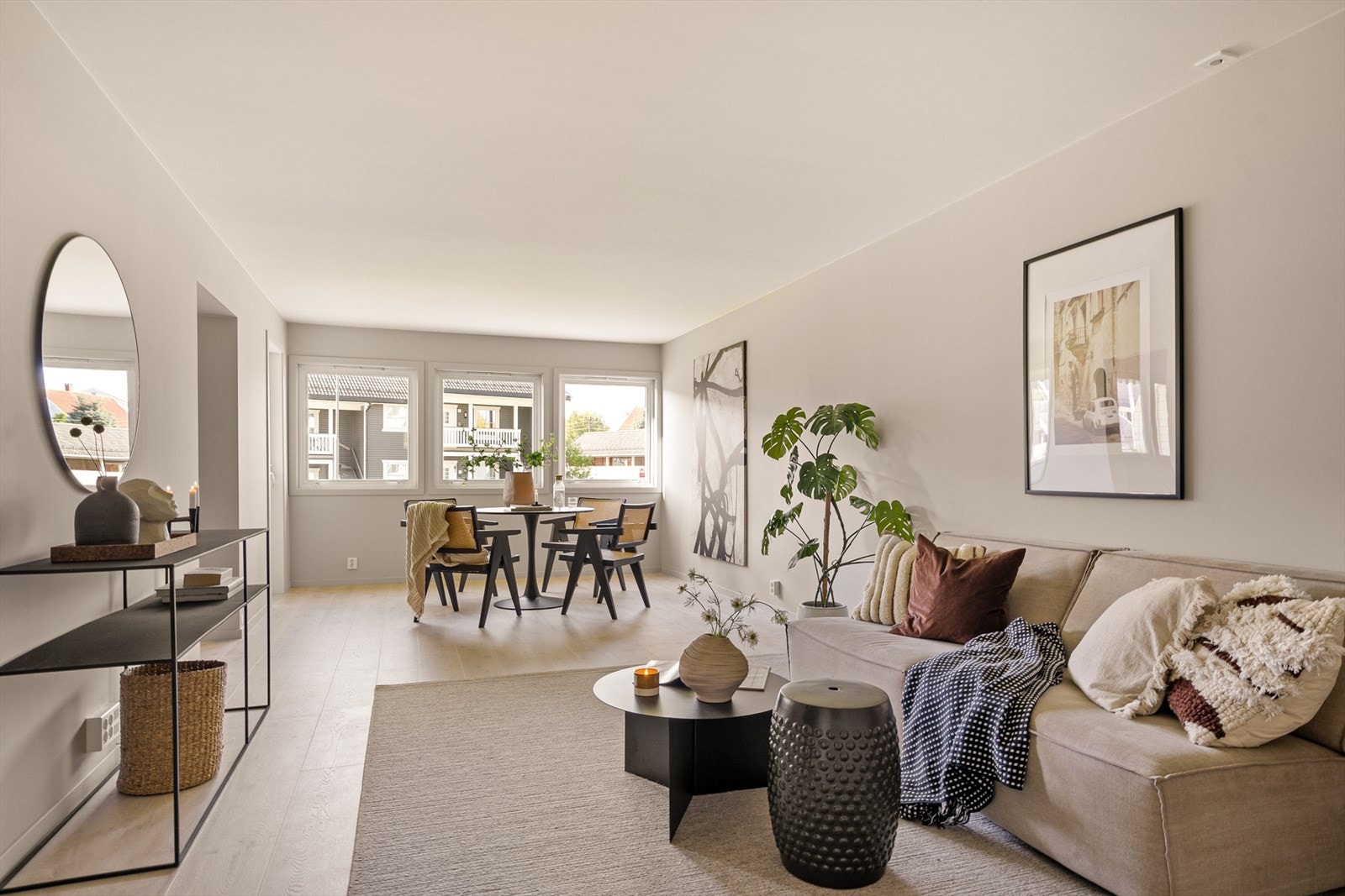 Stue med delvis åpen løsning mot kjøkken og utgang til solrik balkong Galleribilde