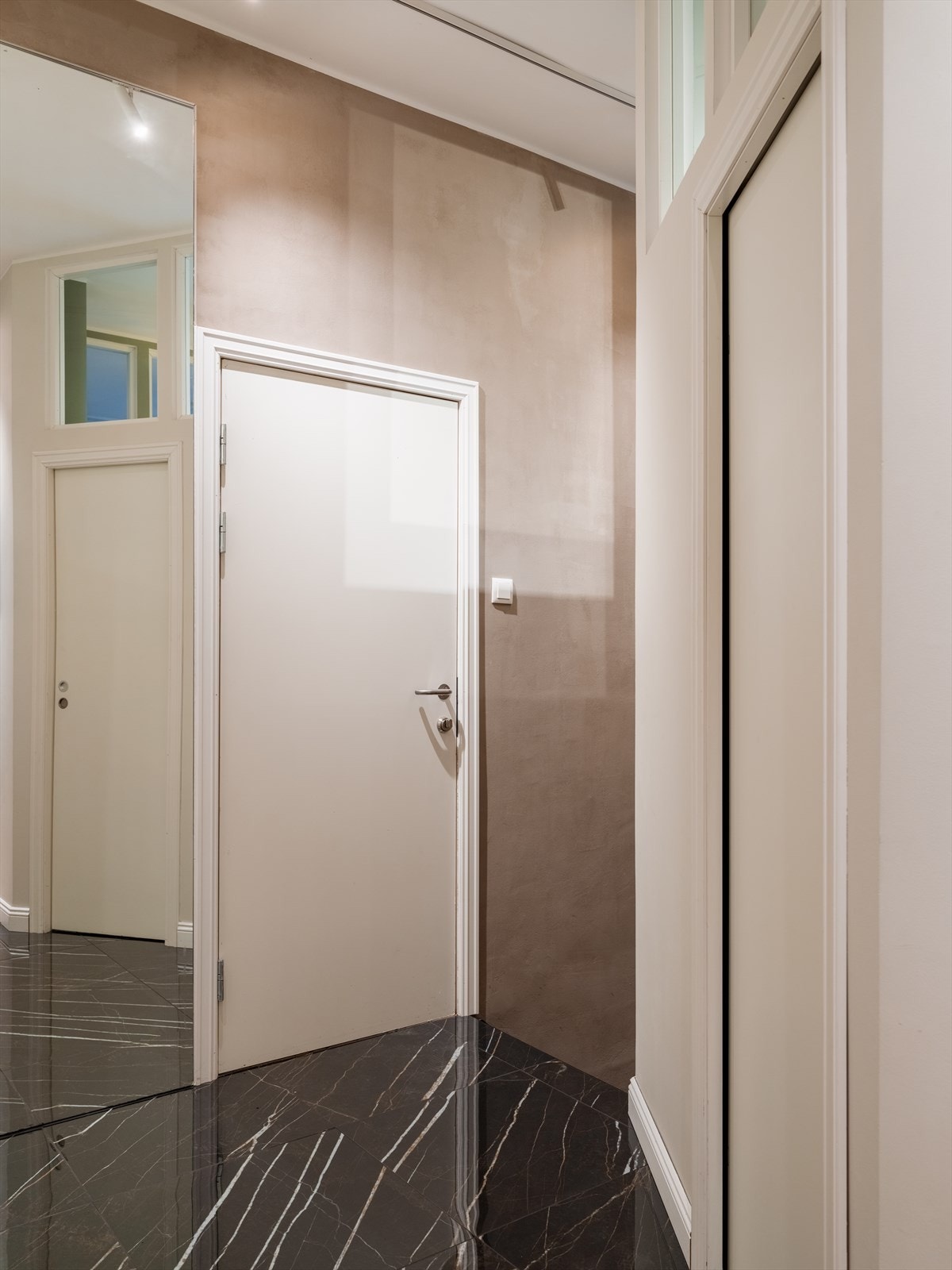 De mørke, marmormønstrede flisene skaper en elegant overgang mellom sonene. Galleribilde