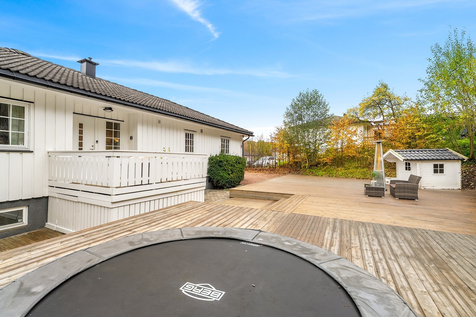 Familievennlig uteområde med nedfelt trampolinegrop som går naturlig sammen med plattingen Galleribilde