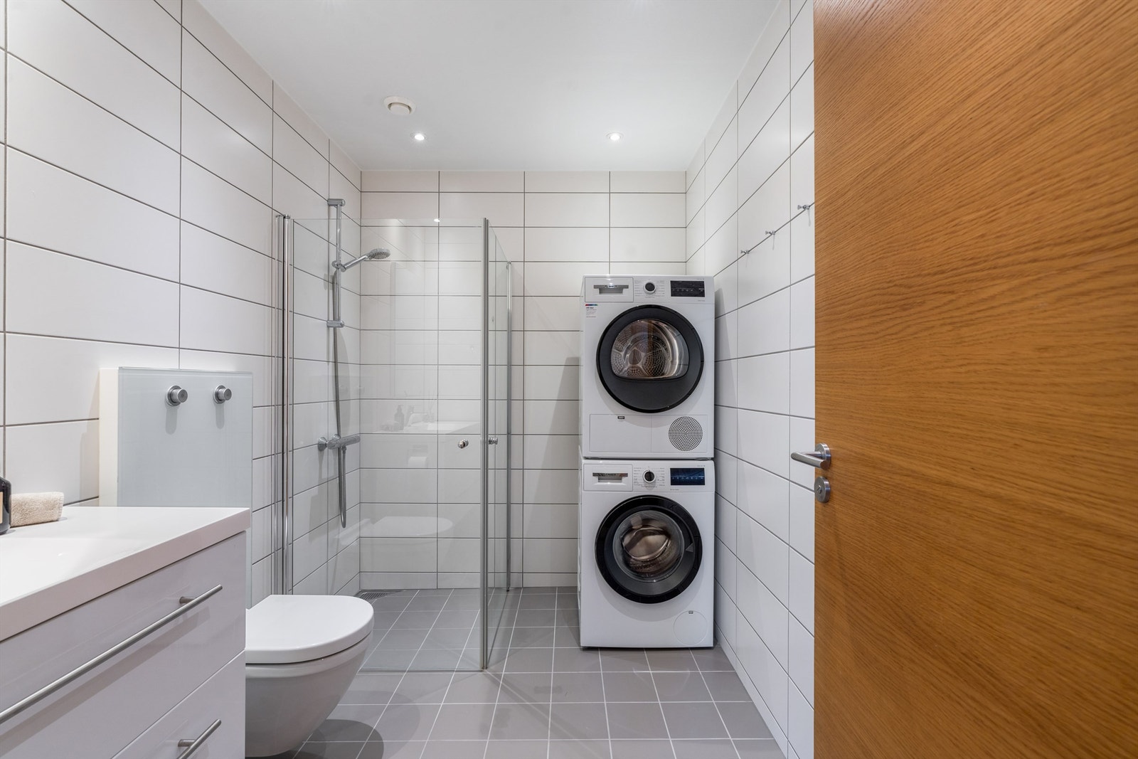 Det er videre utstyrt med vegghengt servantinnredning, dusjhjørne, vegghengt toalett og opplegg for vaskemaskin Galleribilde