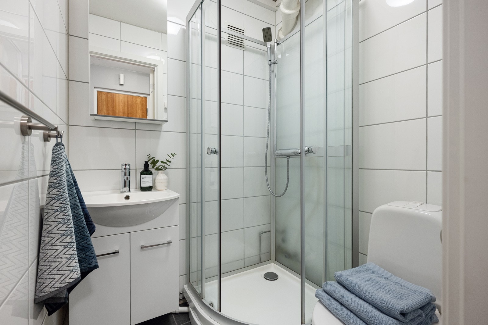 Her er det dusjkabinett, klosett, servant, benkeskap med glatte fronter samt overskap med speilfront. Galleribilde