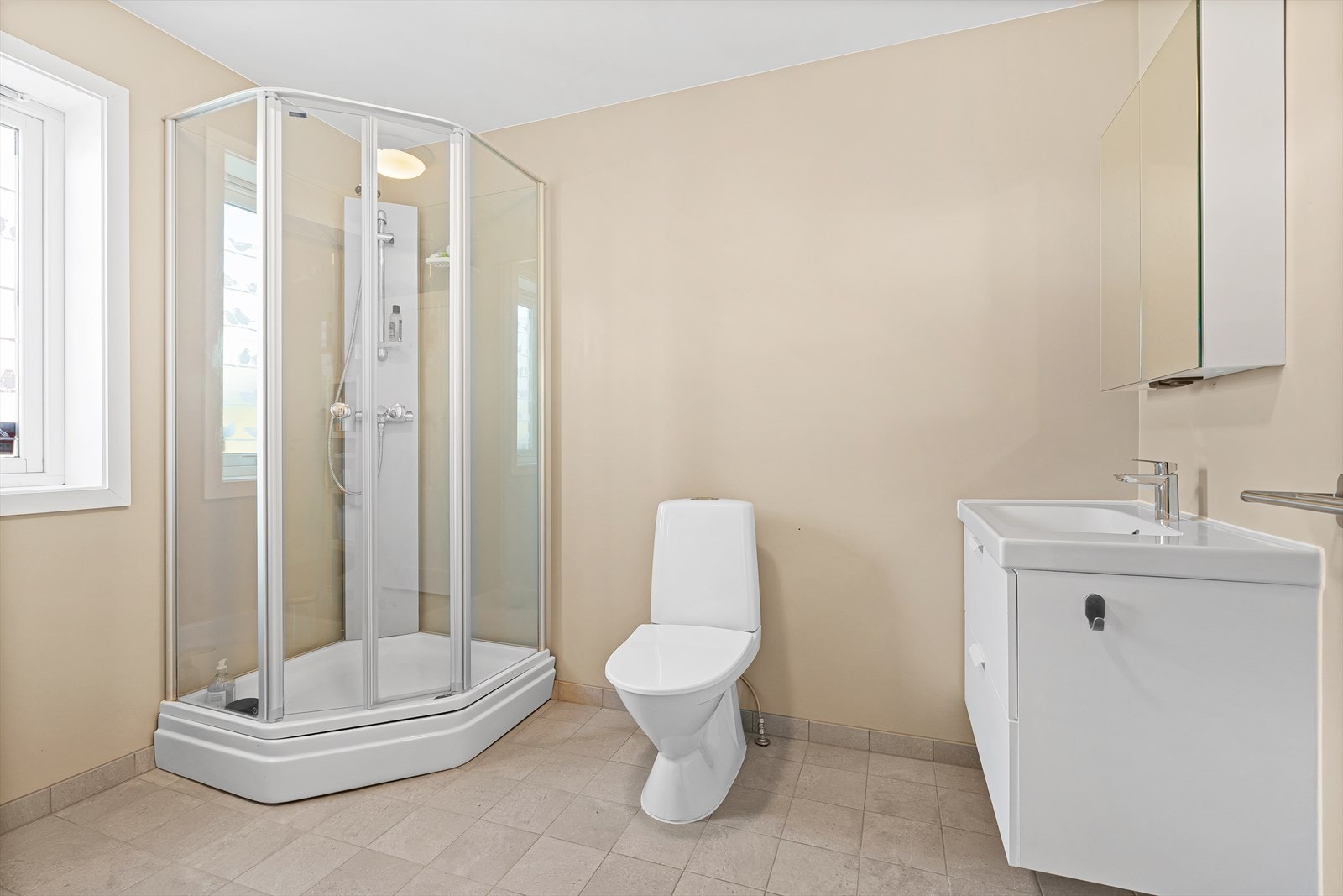 Badet har fliser på gulvet med varmekabler, og inneholder forøvrig et dusjkabinett, toalett, baderomsinnredning med speilskap over, samt plass og opplegg for vaskemaskin/tørketrommel. Galleribilde