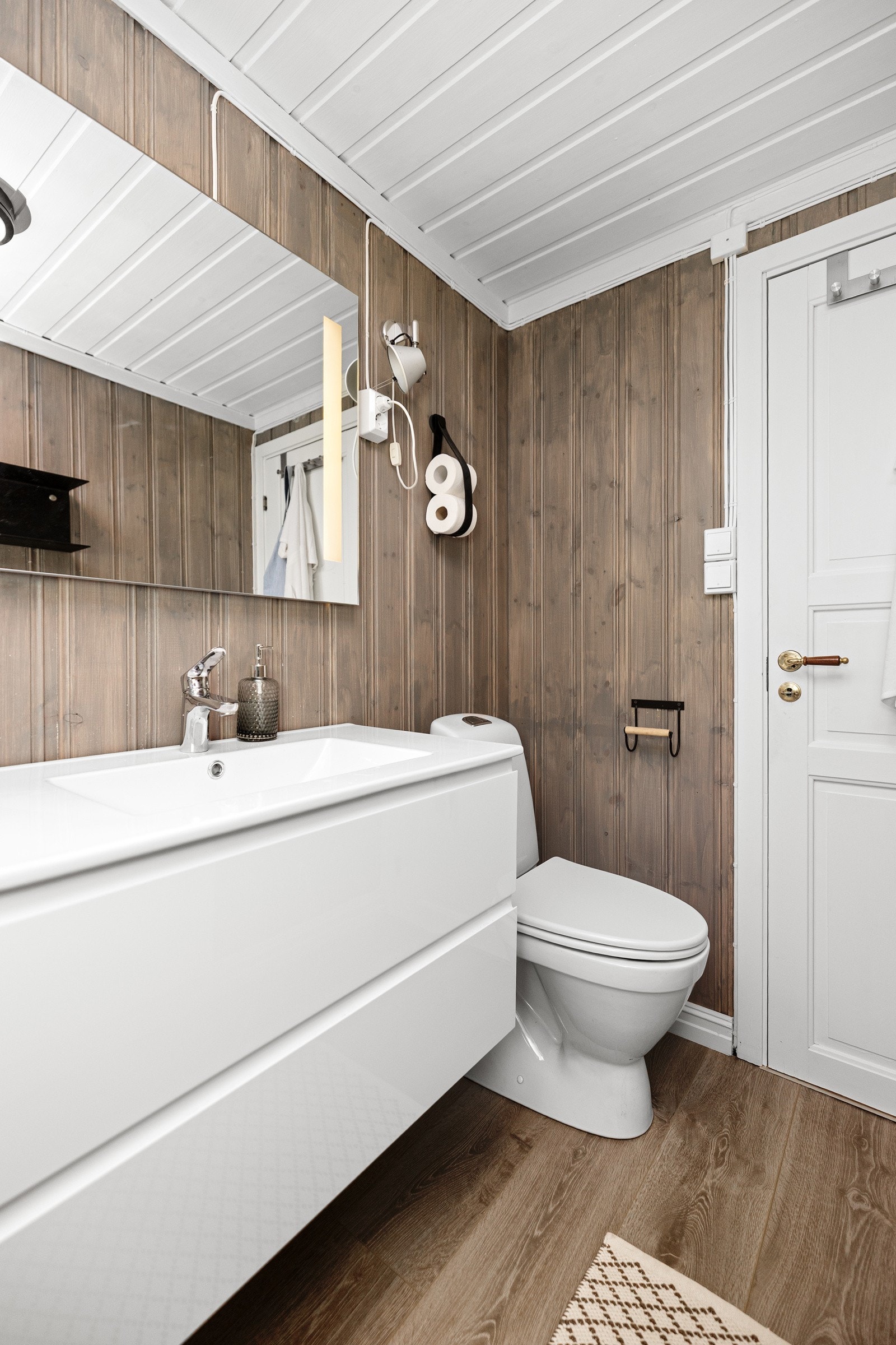 Badet er innredet med dusjkabinett med avrenning direkte til sluk, servantskap med nedfelt servant, gulvmontert toalett samt panelovn på vegg. Galleribilde