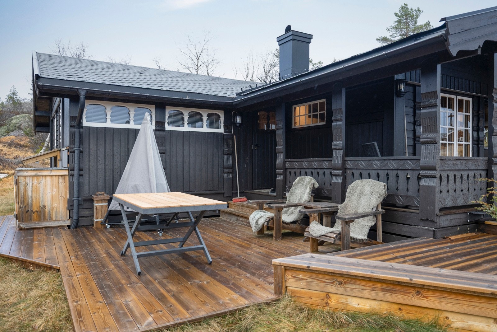 Hytta sett fra uteplass med flere soner for sittegrupper. Galleribilde