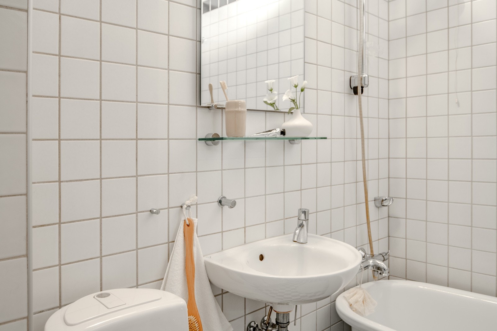 Badet er innredet med toalett, servant, speil med overlys, veggskap og badekar. Galleribilde