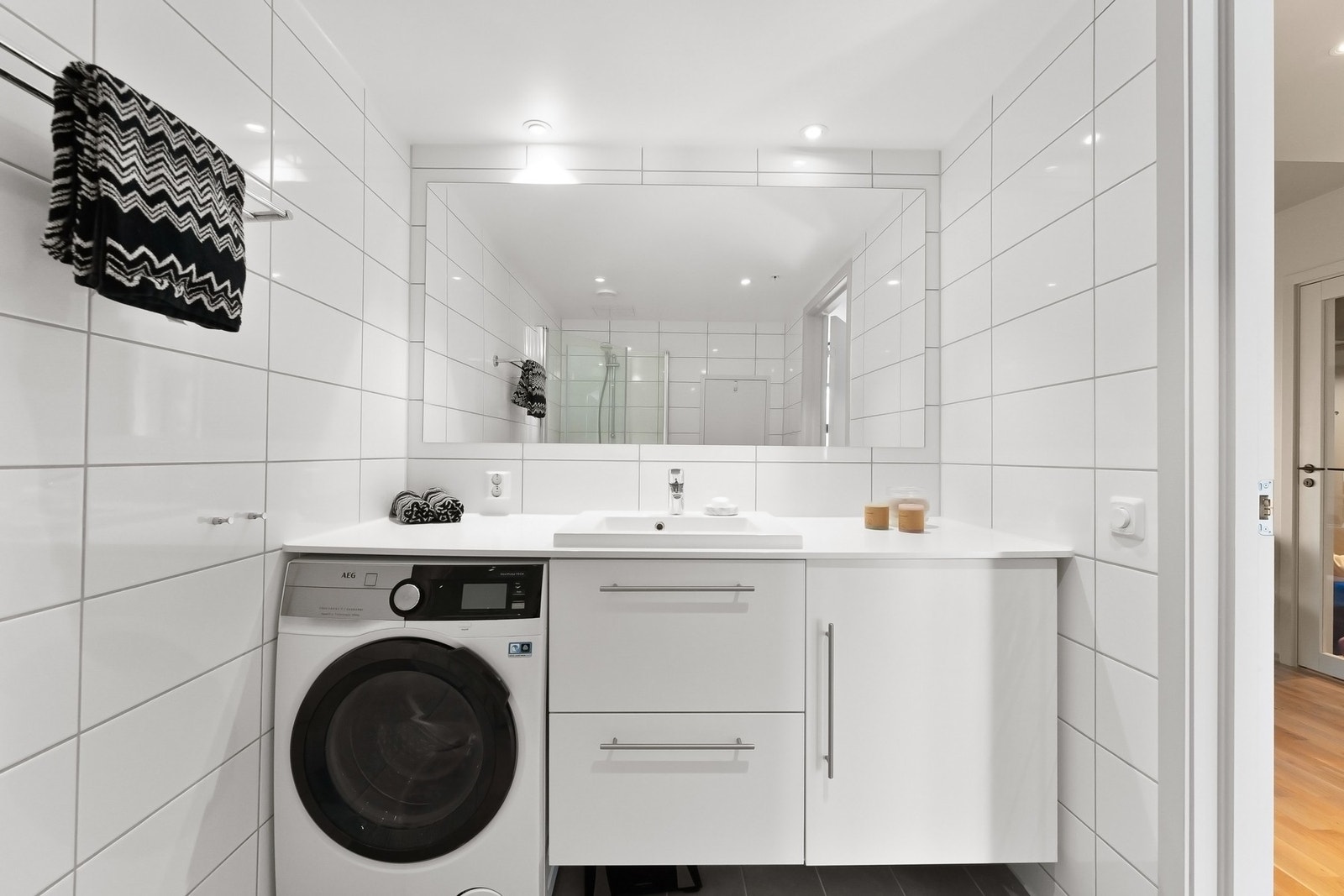 Flislagt baderom med gulvvarme, dusjhjørne og opplegg for vaskemaskin Galleribilde