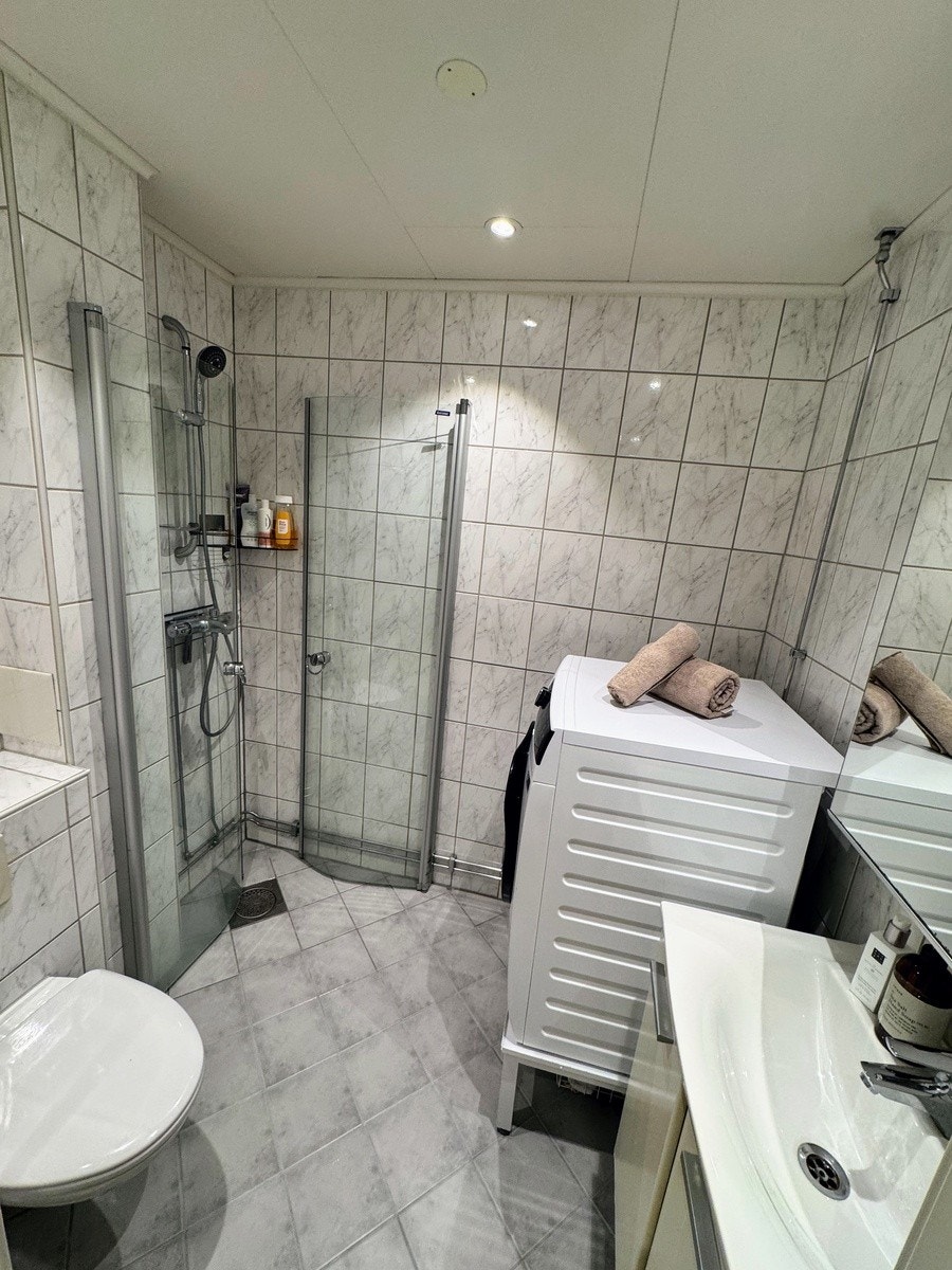 Flislagt bad med dusj-hjørne og vaskemaskin Galleribilde