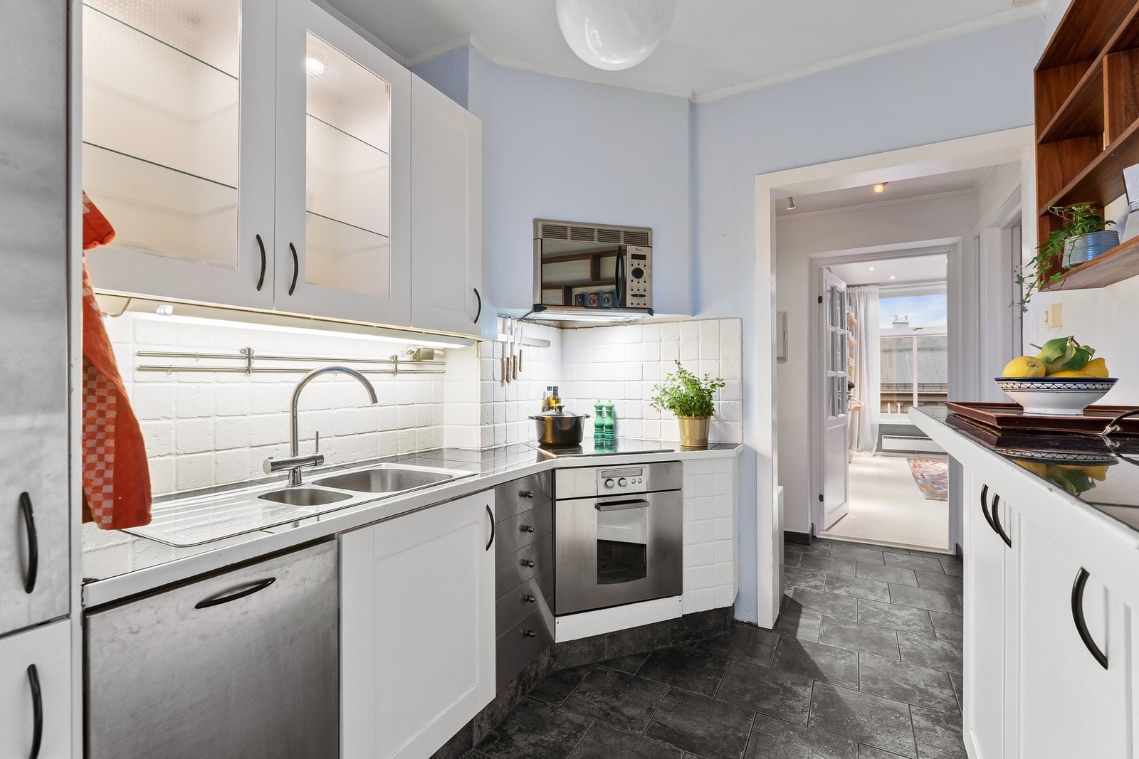 Videre bys det på flislagt benkeplate med nedfelt kum i rustfritt stål og belysning under overskap. Galleribilde