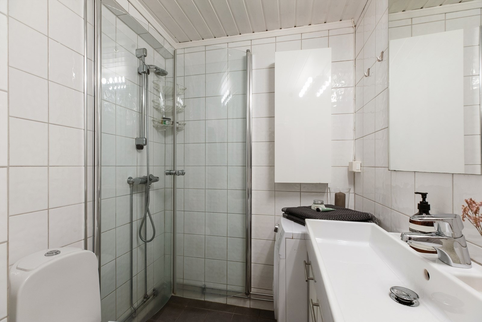 Badet inneholder frittstående toalett, dusj, servant og servantskap. Opplegg for vaskemaskin. Galleribilde