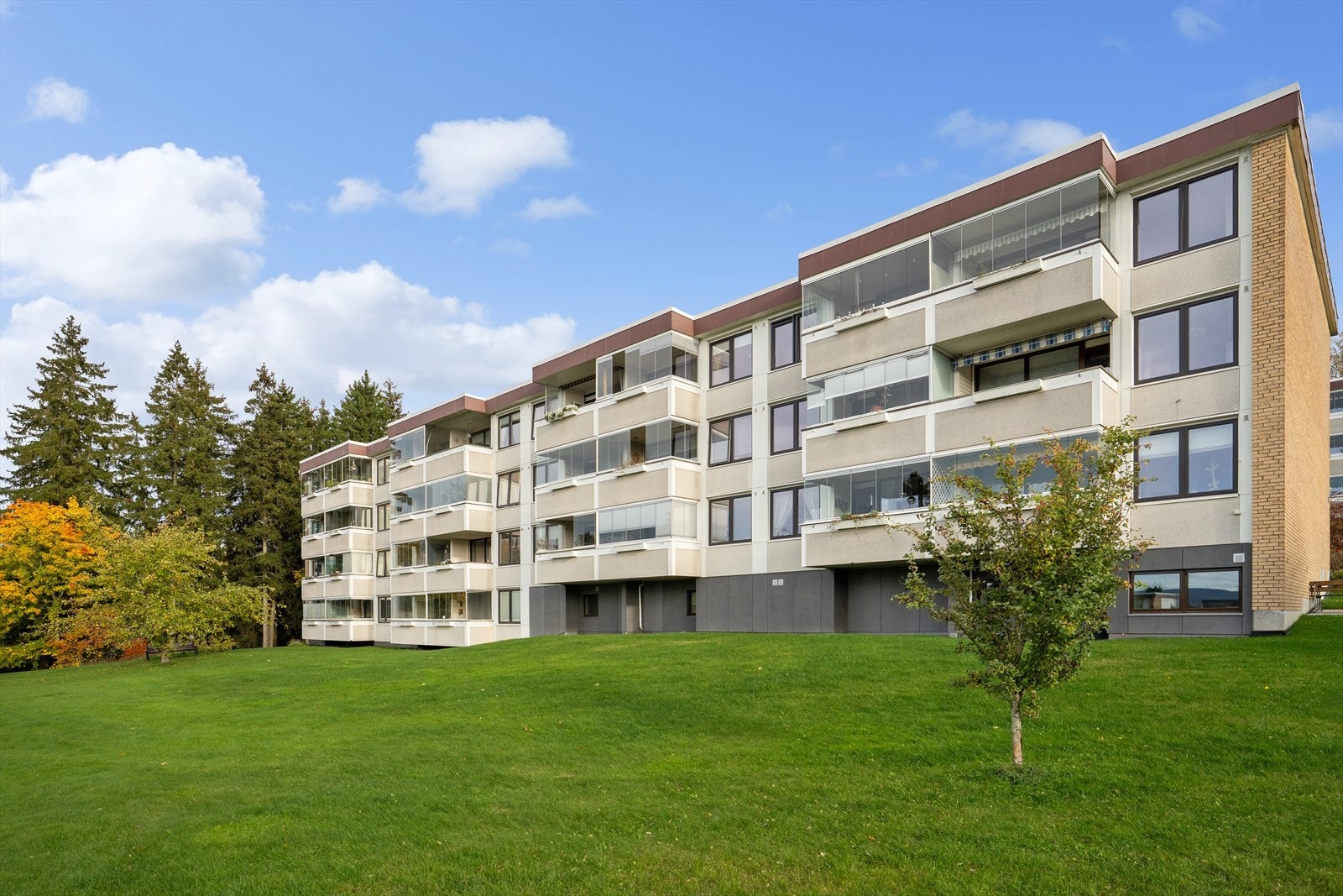 Pent opparbeidede grøntarealer med busker, trær, sitterbenker m.m. Galleribilde