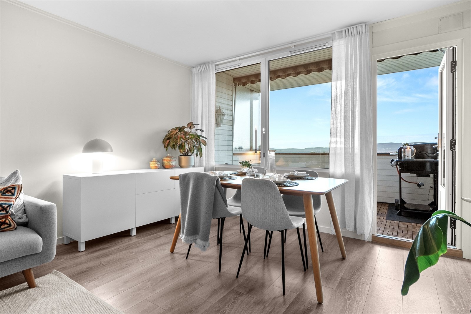 Nyt middagen i romslig spisestue med utsikt mot balkong og kveldssol. Galleribilde