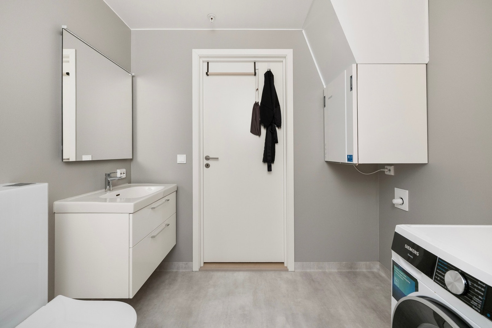 Helstøpt servant på en moderne skuffeseksjon. På badet er det opplegg for vaskemaskin. Galleribilde