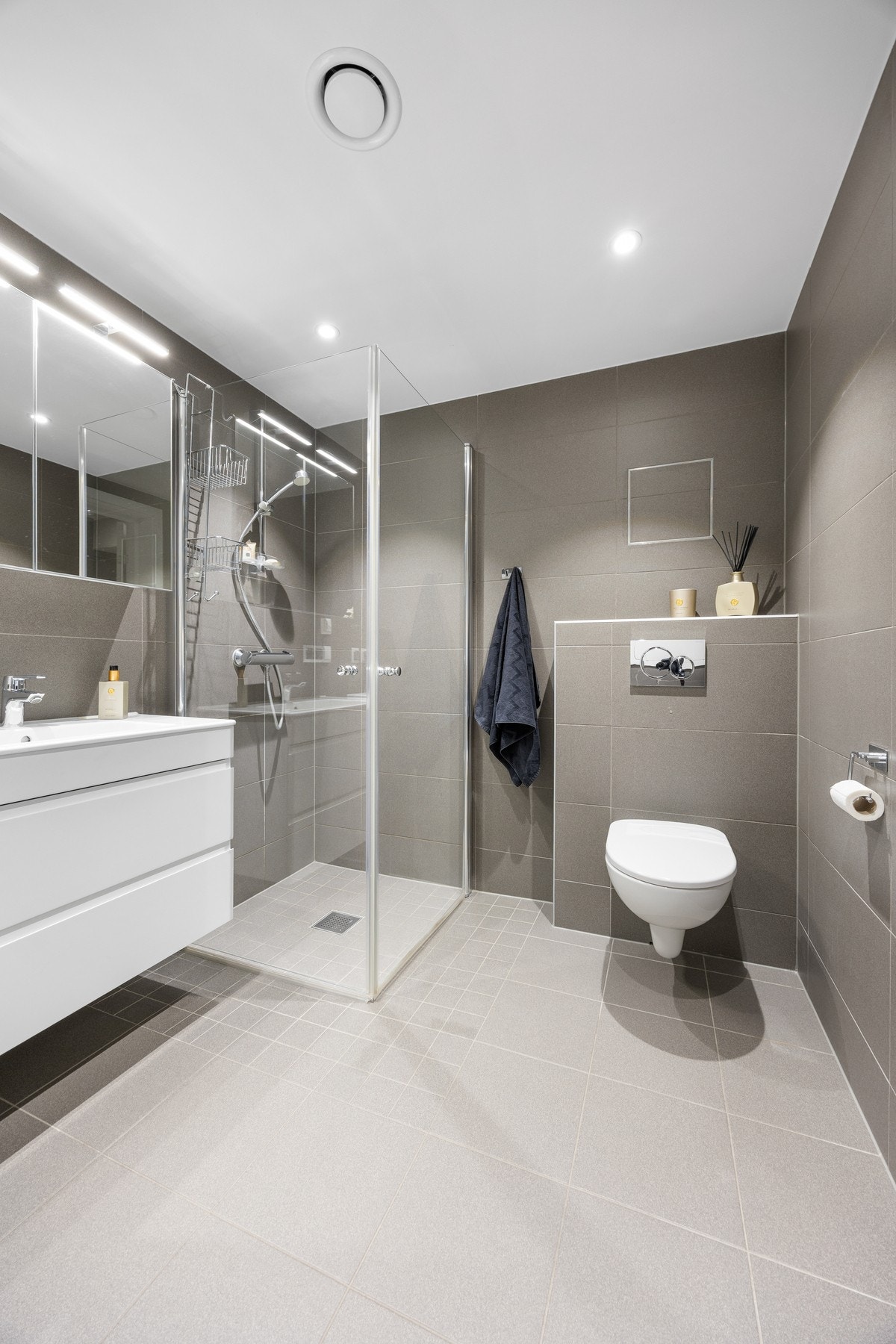 Videre er det vegghengt toalett og dusjhjørne med hånddusj og innfellbare dusjvegger i glass. Rommet har opplegg for vaskemaskin. Galleribilde