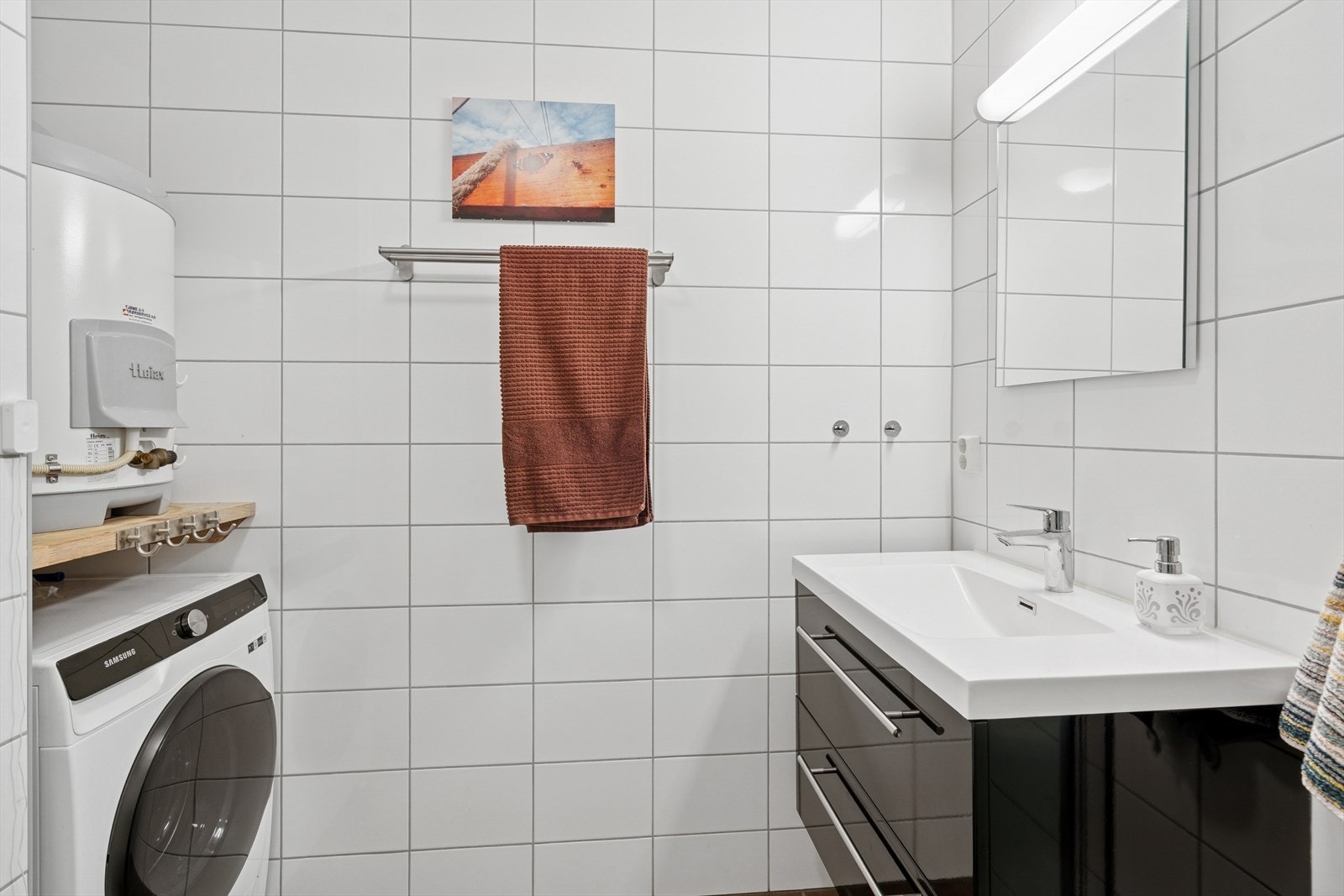 Pent baderom fra byggeår med lyse fliser og tidløst uttrykk - praktisk innredet og godt vedlikeholdt Galleribilde