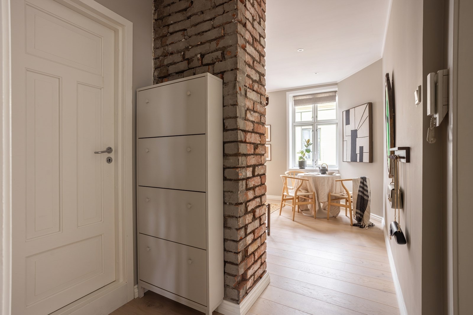 Entré med bl.a. eksponert teglstein og dørcalling på vegg Galleribilde