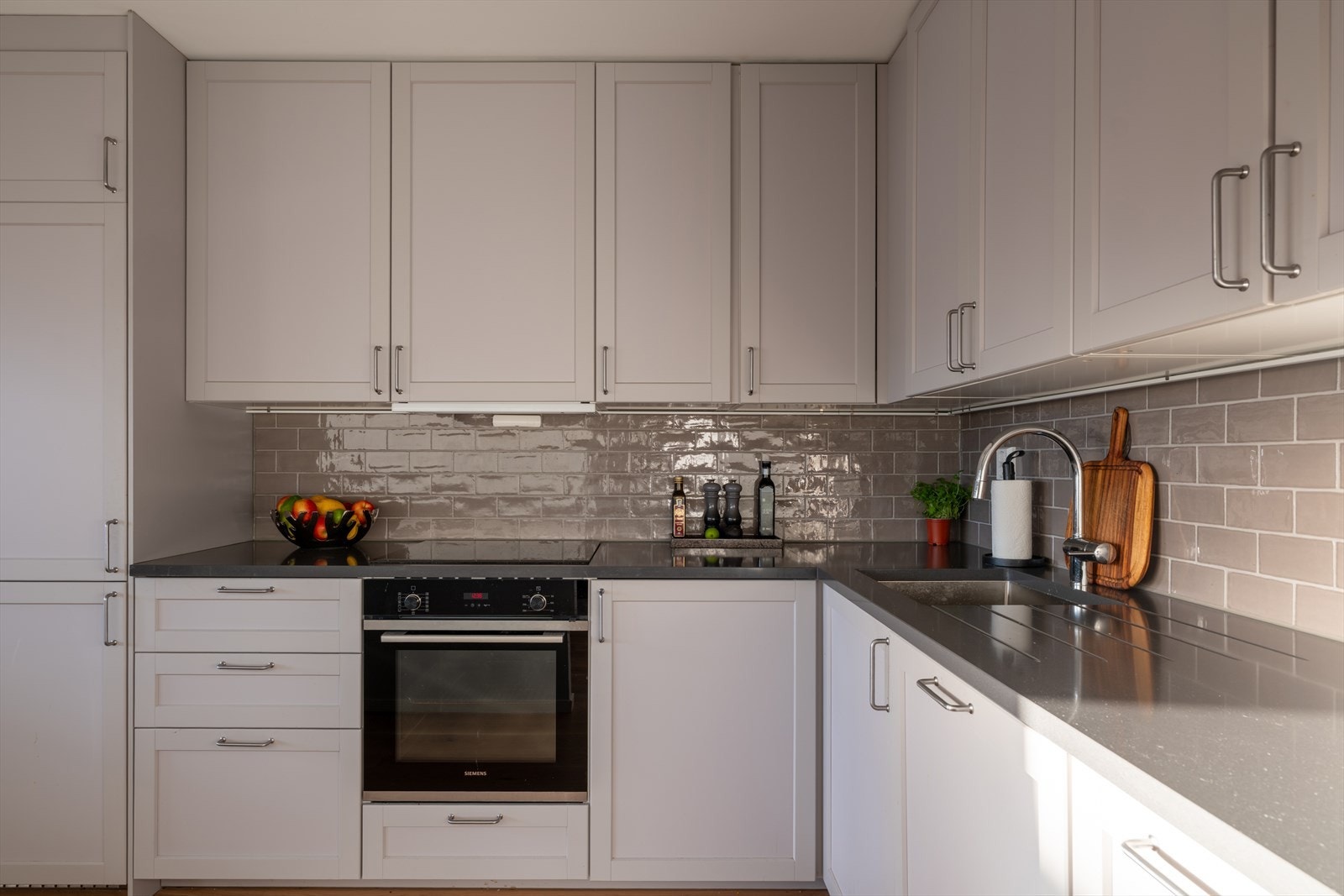 Her får du et flott kjøkken med glatte fronter og benkeplate i steinkompositt Galleribilde