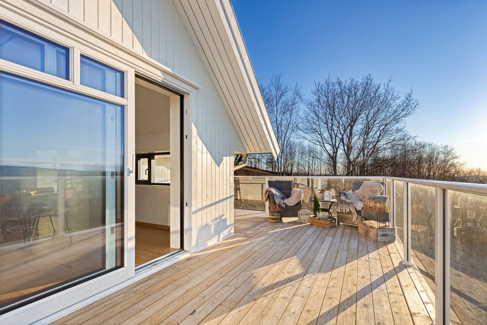 Utsikt terrasse ved stue. Bruksunderlag med terrassebord i tre, og rekkverk i glass og stål. Galleribilde