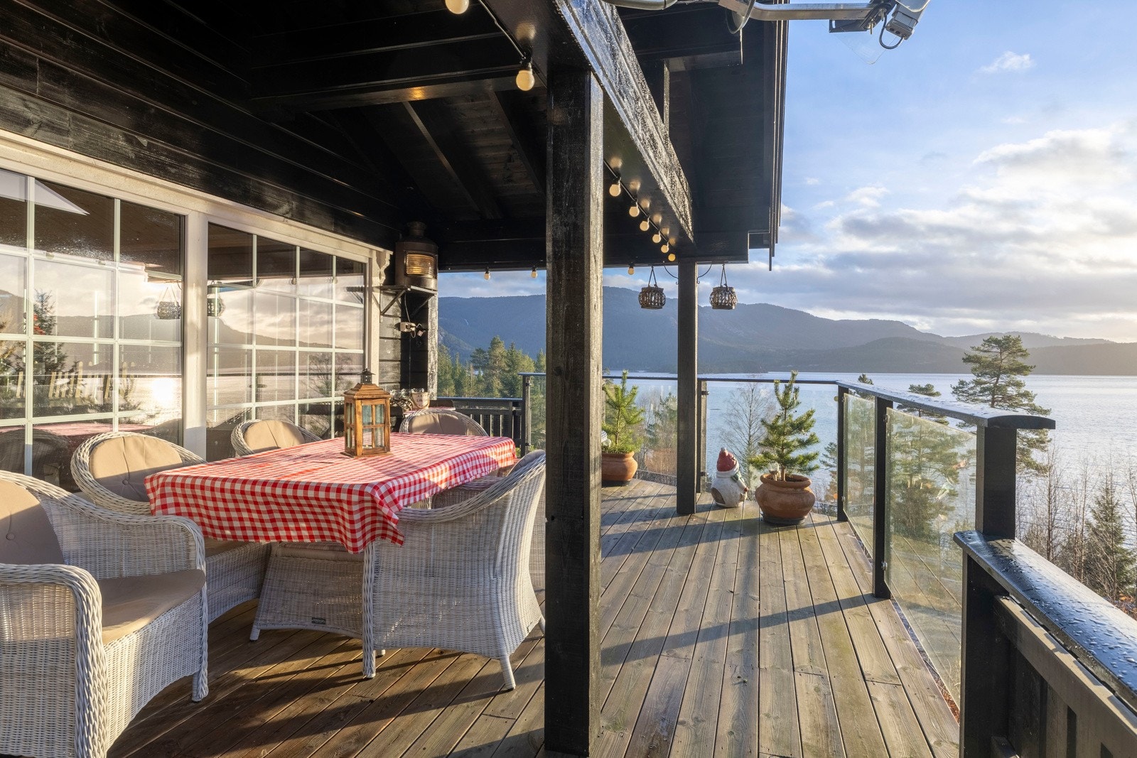 Overbygget terrasse med sittegruppe og utsikt mot vann og fjell. Galleribilde