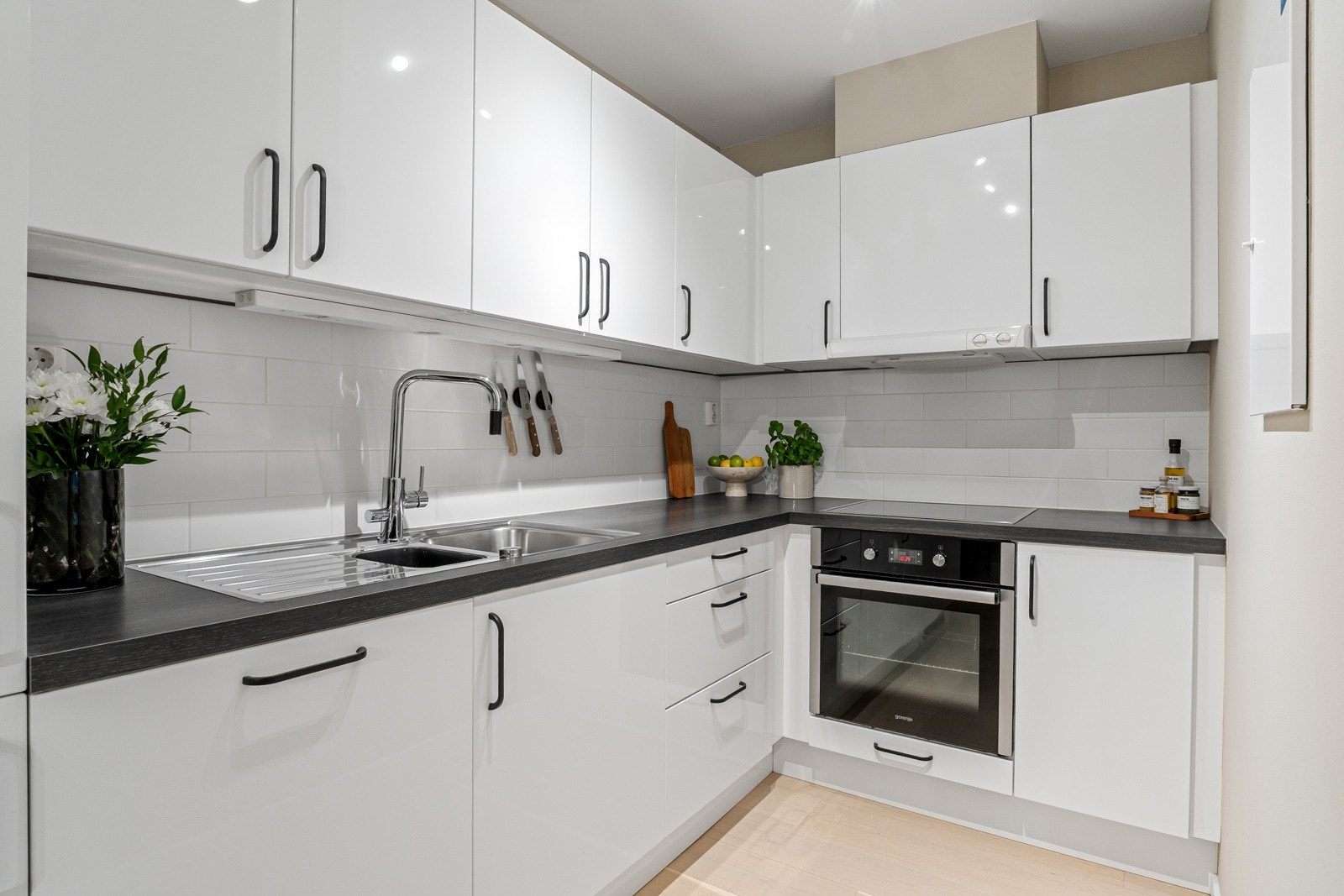 Veggene er kledd med fliser som gir et rent og moderne uttrykk. Den mørke laminatbenkeplaten har planlimt vask og ett-greps armatur i krom. Galleribilde