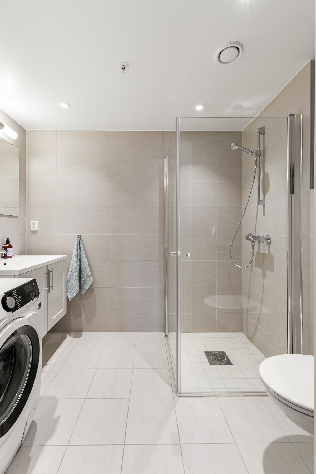 Tidløst og flott flisvalg med hvit servantinnredning, hvit heldekkende servant, krom blandebatteri og speil på vegg Galleribilde