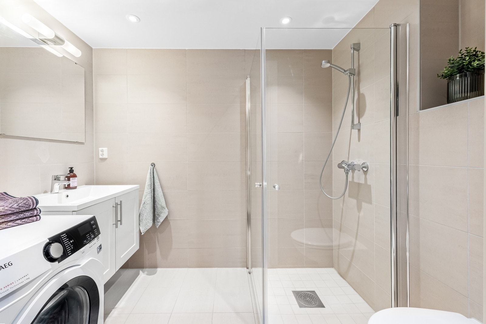 Stort og fint hovedbad med gulvvarme, downlights og opplegg for både vaskemaskin og tørketrommel Galleribilde