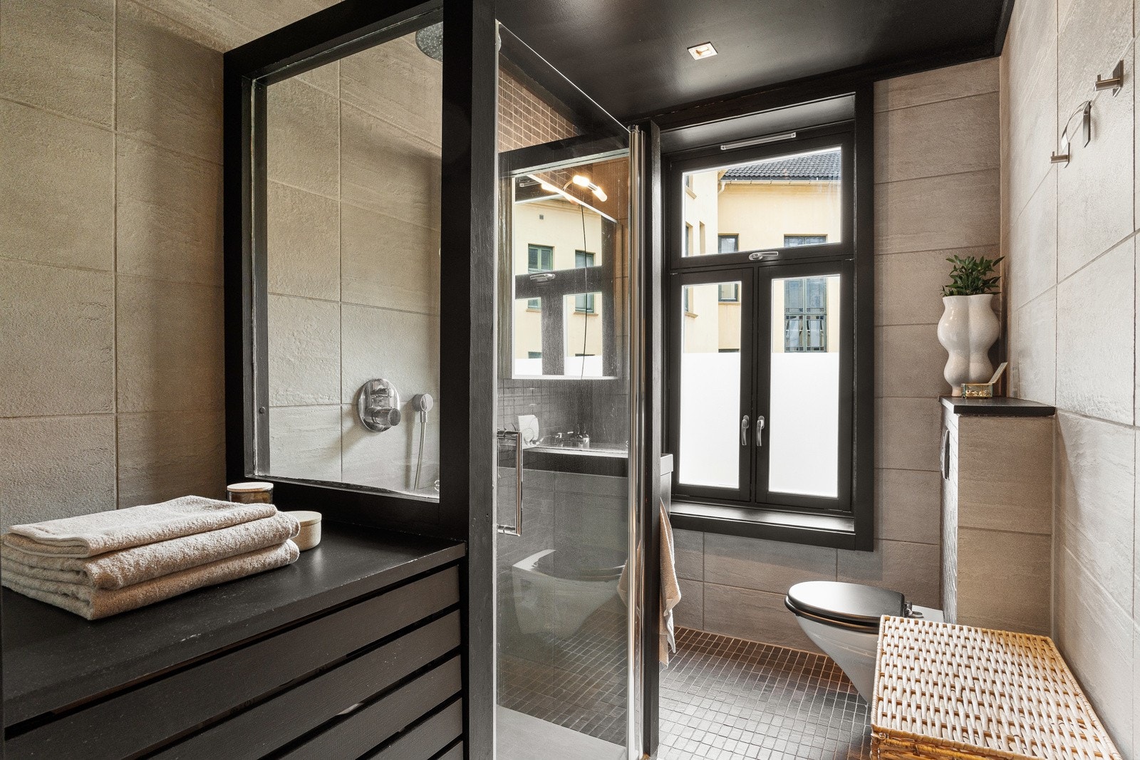 Delikat og flislagt baderom med varmekabler. Badet er innredet med vegghengt servantskap, servant, speilskap med belysning og vegghengt toalett. Galleribilde