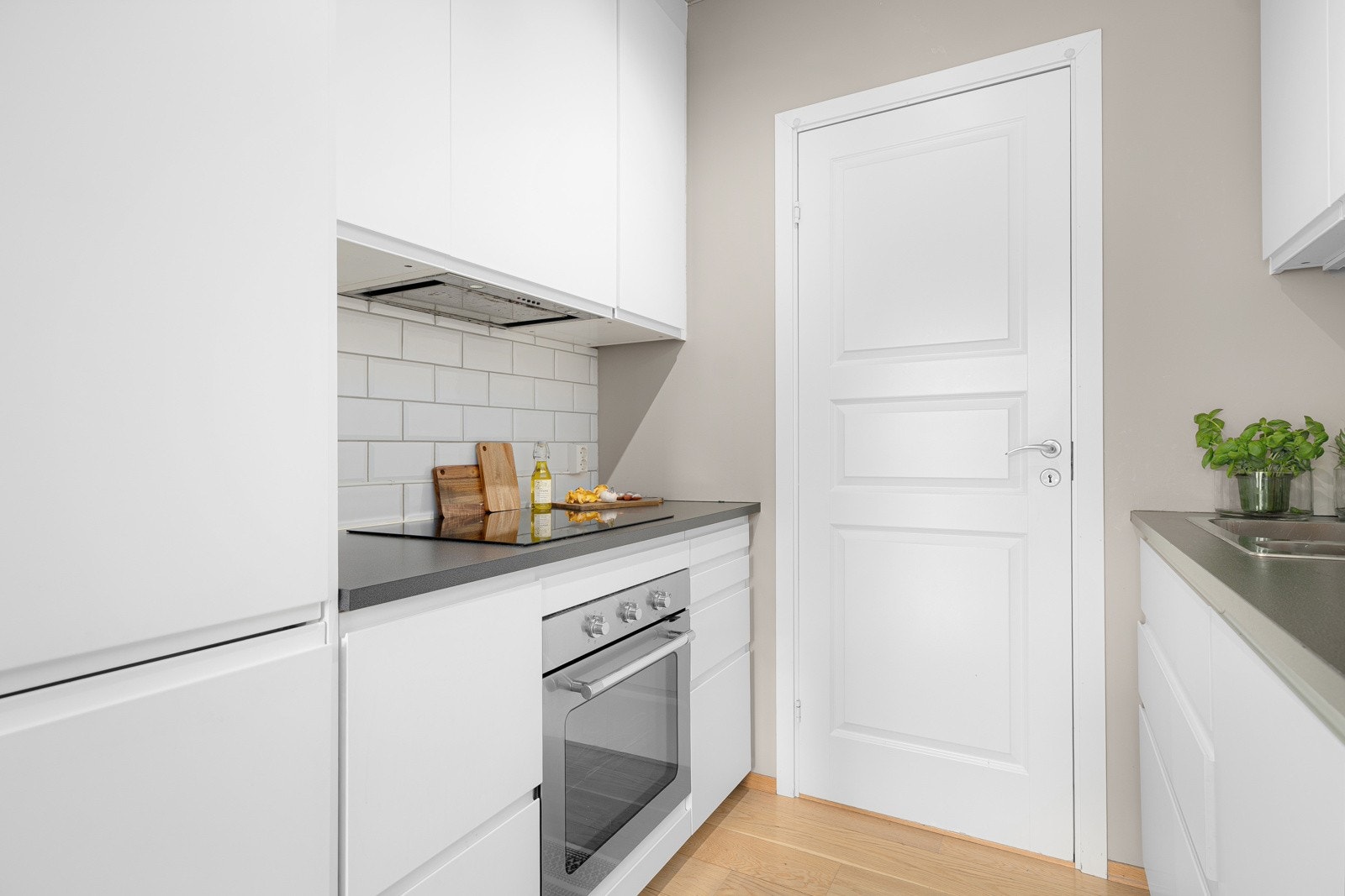 Moderne kjøkkeninnredning fra 2017 med god skap- og benkeplass. Innredningen har hvite glatte fronter og laminert benkeplate med nedfelt oppvaskkum. Både fint og praktisk med flotte fliser i benkeryggen og belysning under de takhøye overskapene. Galleribilde