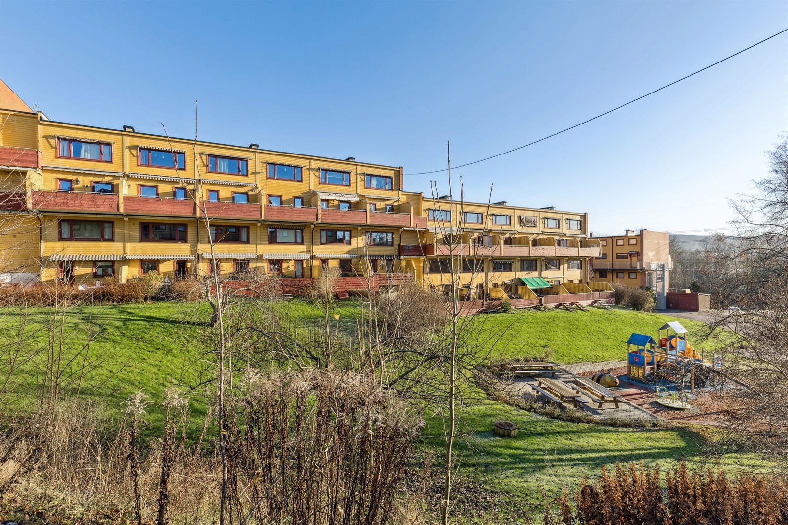 Felles uteområde inkluderer lekeplass og plen for rekreasjon. Galleribilde