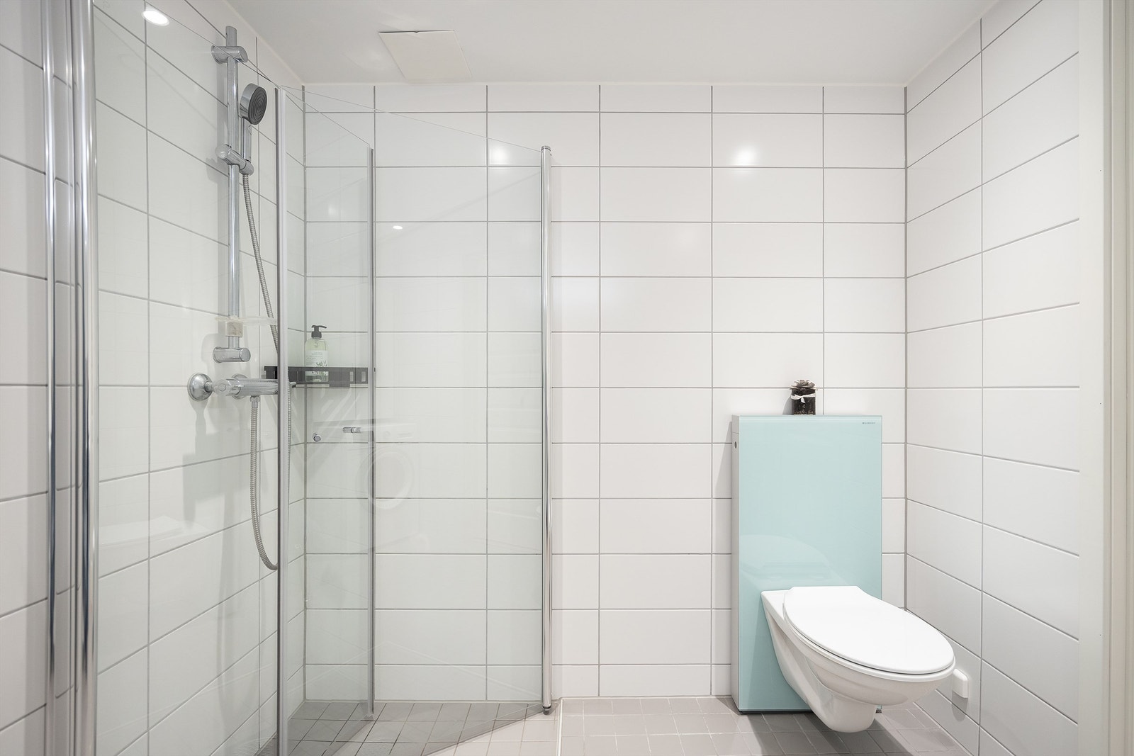 Badet er innredet med vegghengt servantskap og ovenpåliggende servant, speilskap med belysning og dusjsone med innfellbare dører av glass. Galleribilde