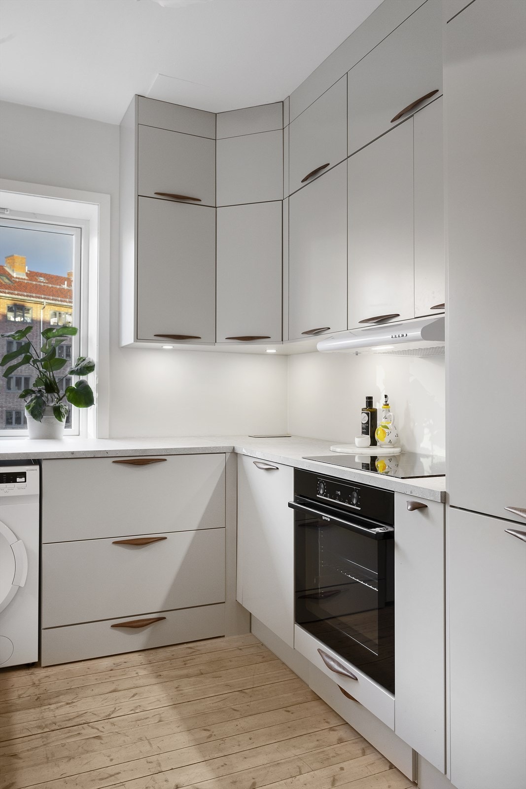 Lys og luftig kjøkkeninnredning med glatte fronter. Praktiske skapløsninger som gir mye oppbevaringsplass. Galleribilde