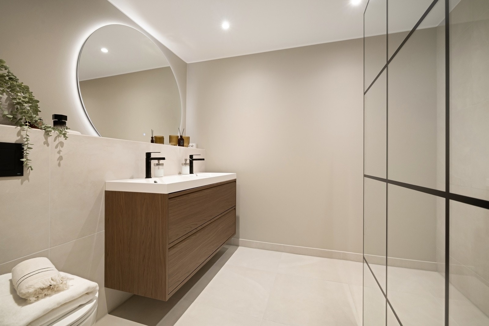 Baderom 1 (Rehabilitert 2025) - Bad med flislagt gulv og varmekabler. Vegger med fliser og malte flater. Speil med belysning, downlights, servant med innredning, dusjhjørne med glassvegg og vegghengt toalett. Galleribilde