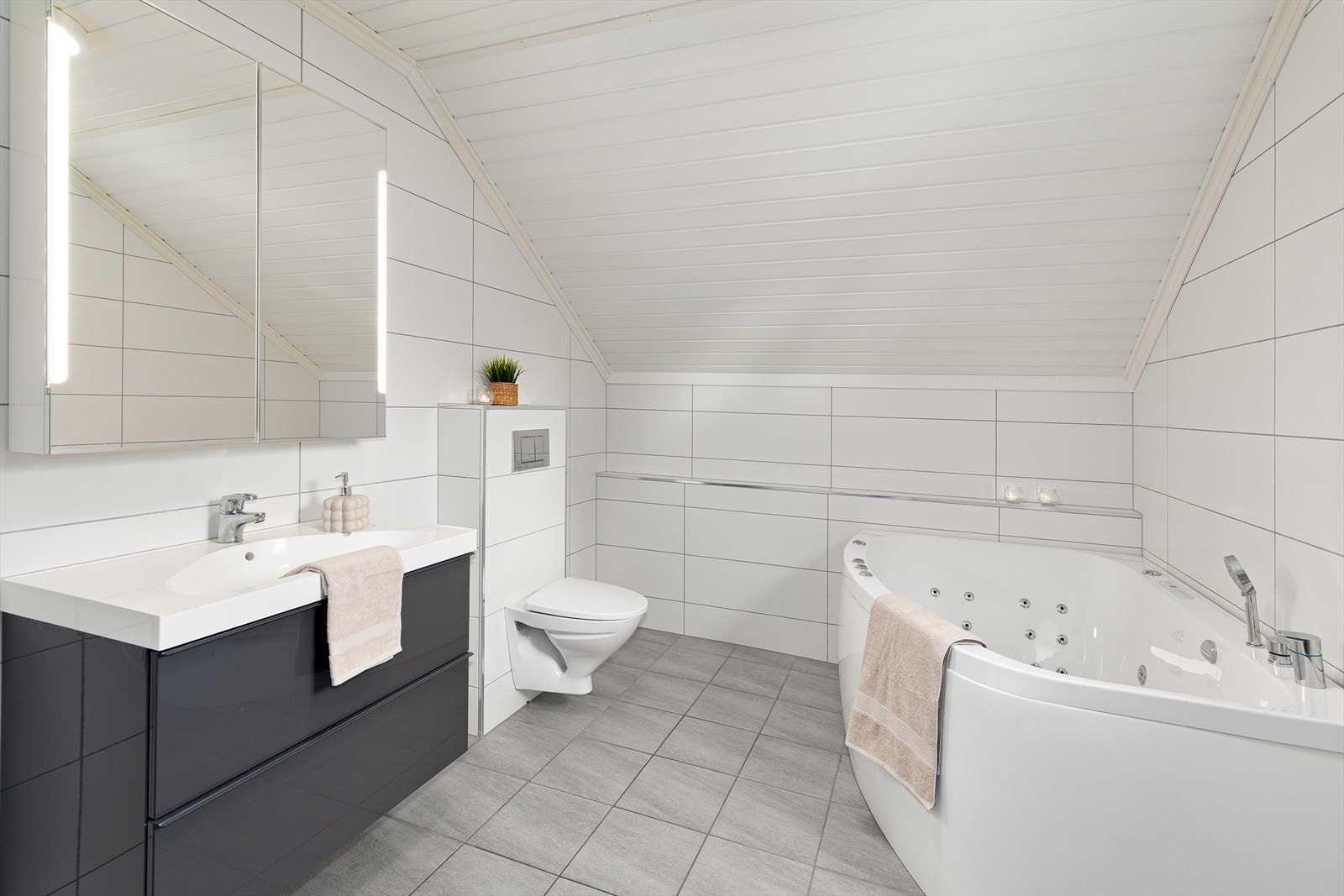 Lyst og delikat bad i andre etasje med flislagte overflater, dusjsone, vegghengt toalett og boblebadekar. Galleribilde