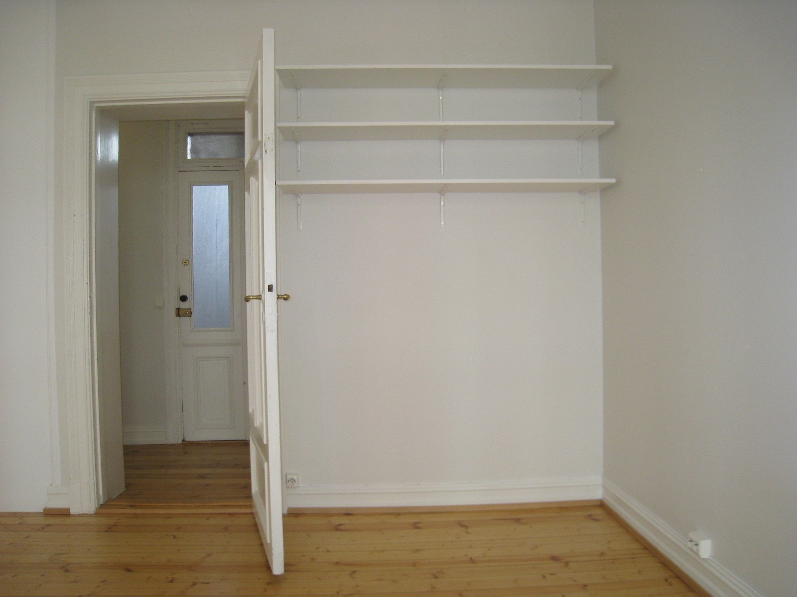 3 bokhyller bak døra i rom 1. Ytterdør i bakgrunnen ble skiftet i 2021 Galleribilde